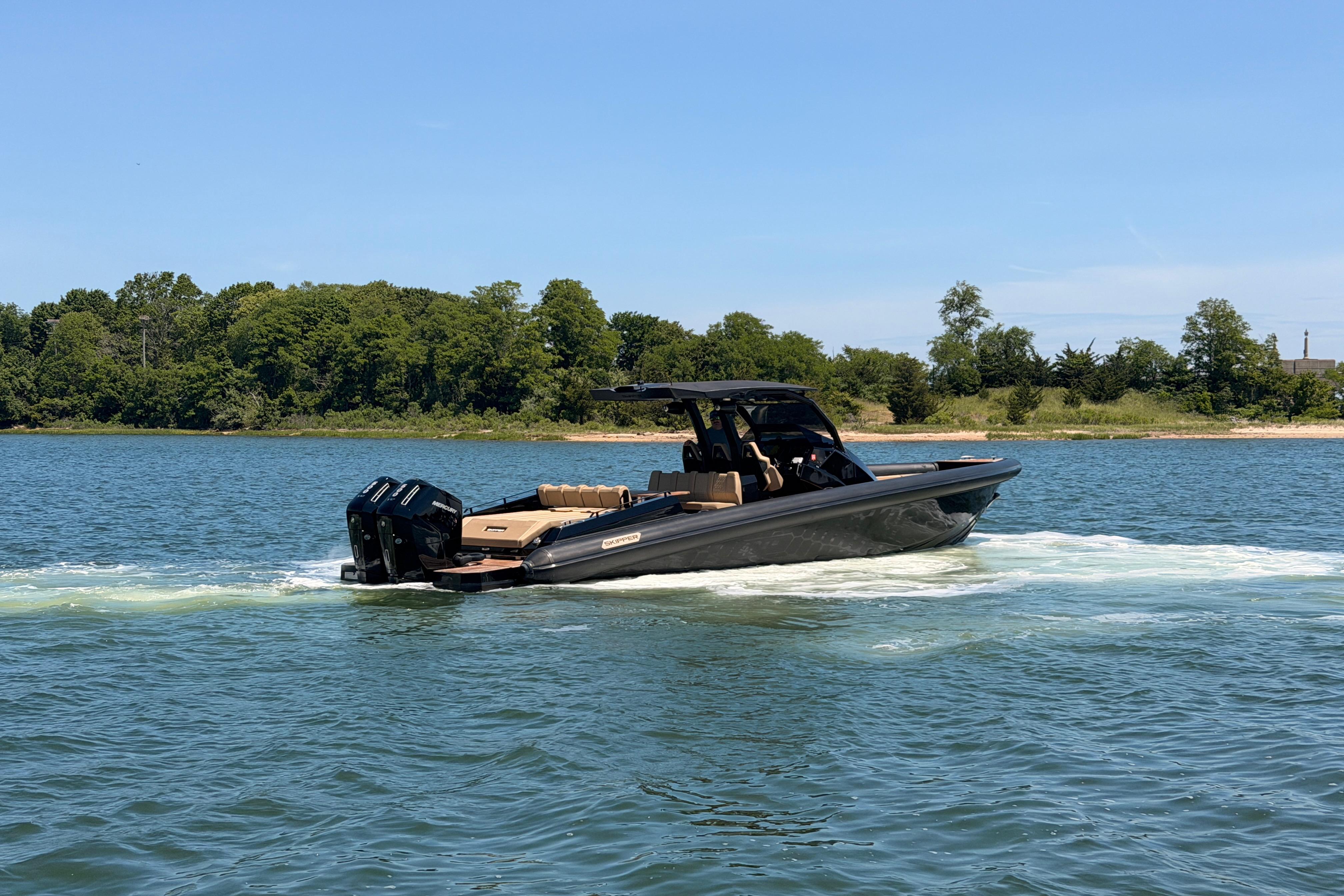 2023 Skipper-BSK 42NC boat cruising on a serene lake with lush green shoreline.