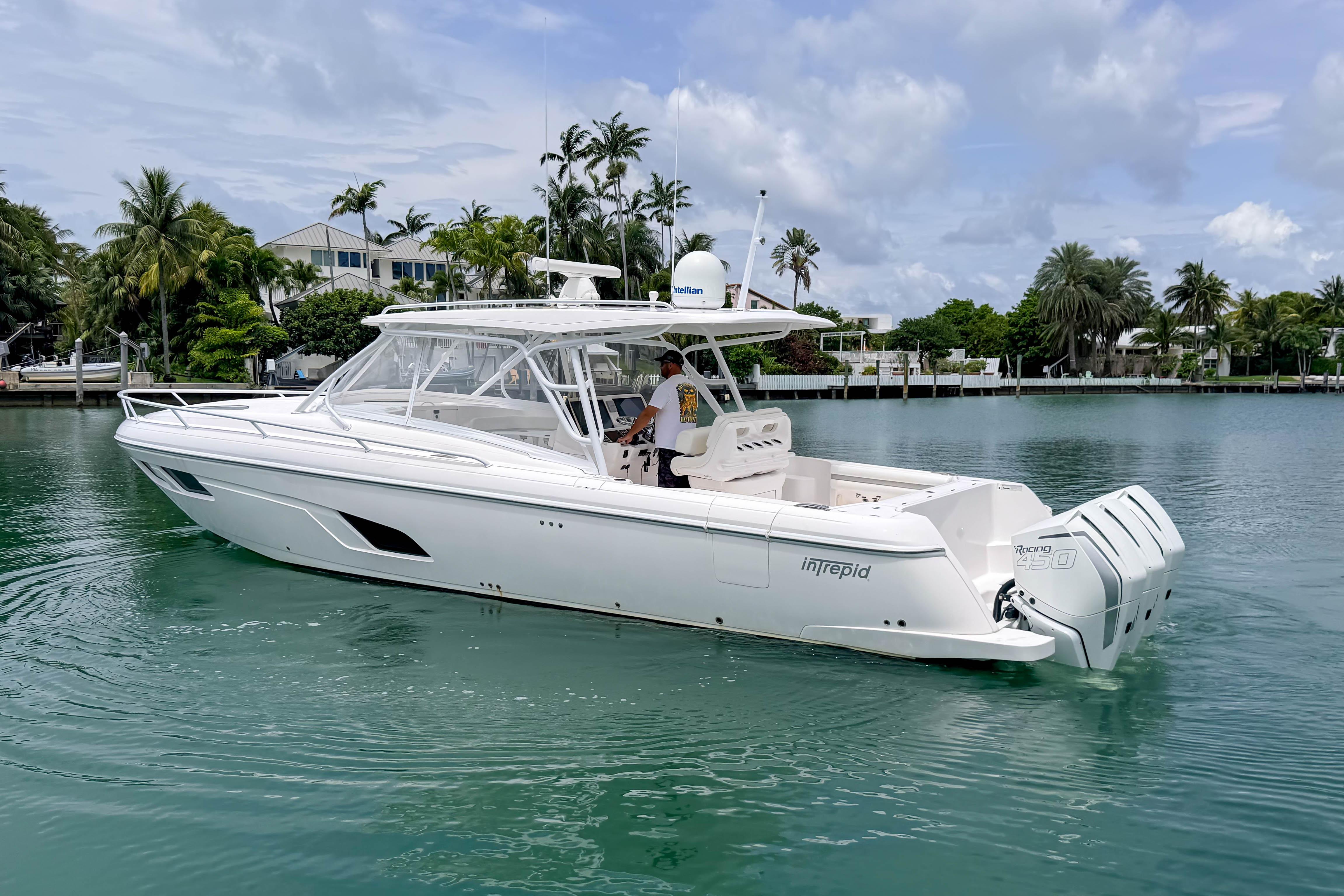 2021 Intrepid 409 Valor boat cruising on a tropical waterway with palm trees.