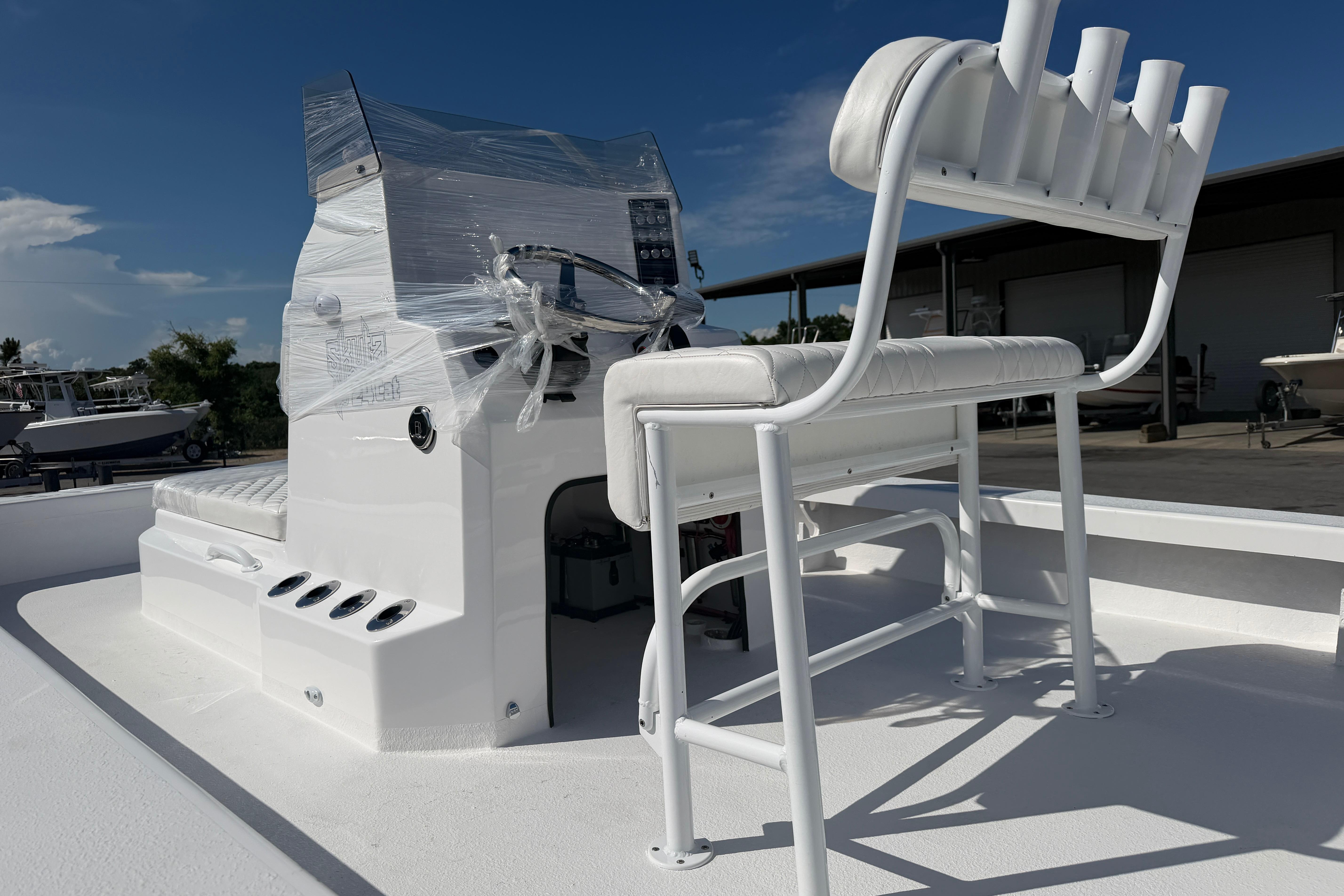2026 Skuta 24 Cat boat with white seating and console, wrapped for protection.