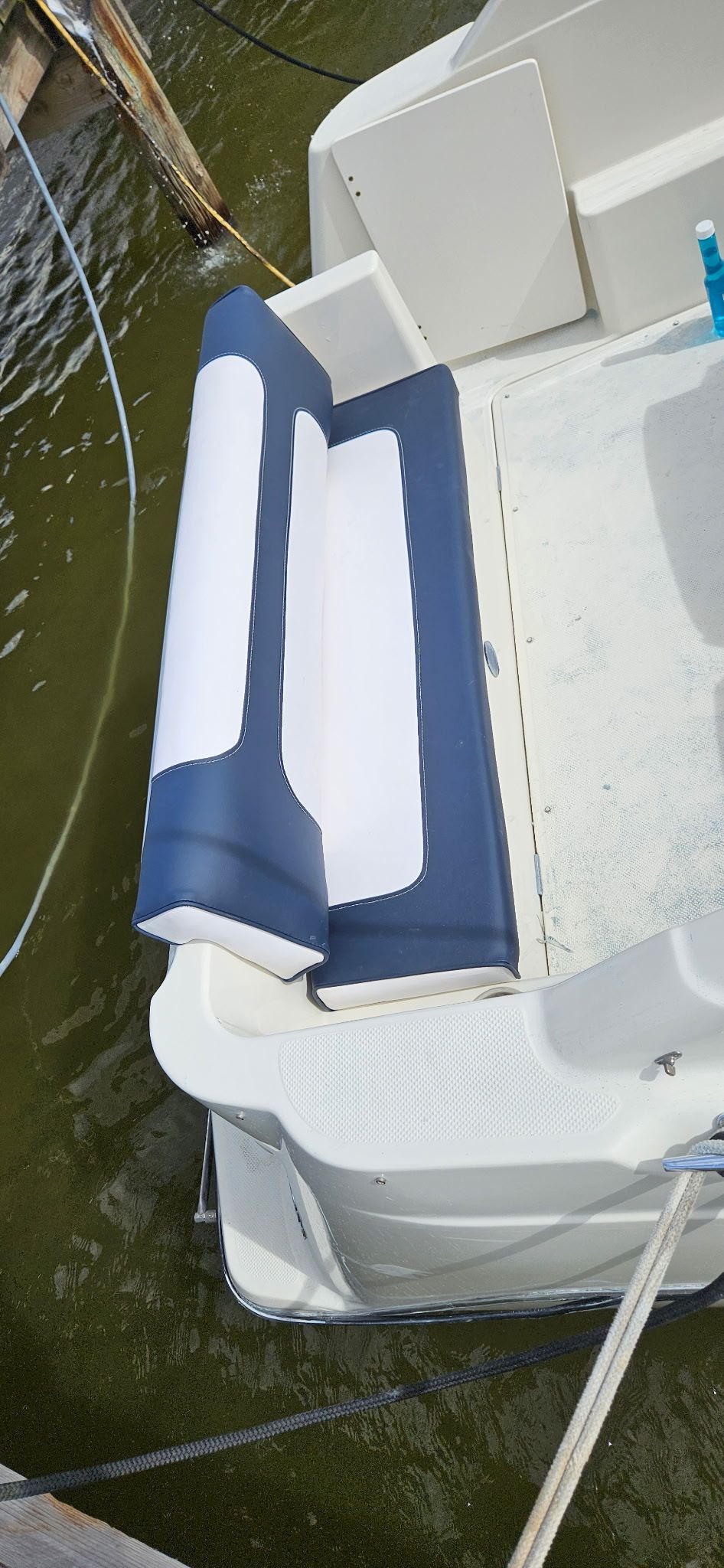 A blue and white seat cushion on a boat docked at a pier.
