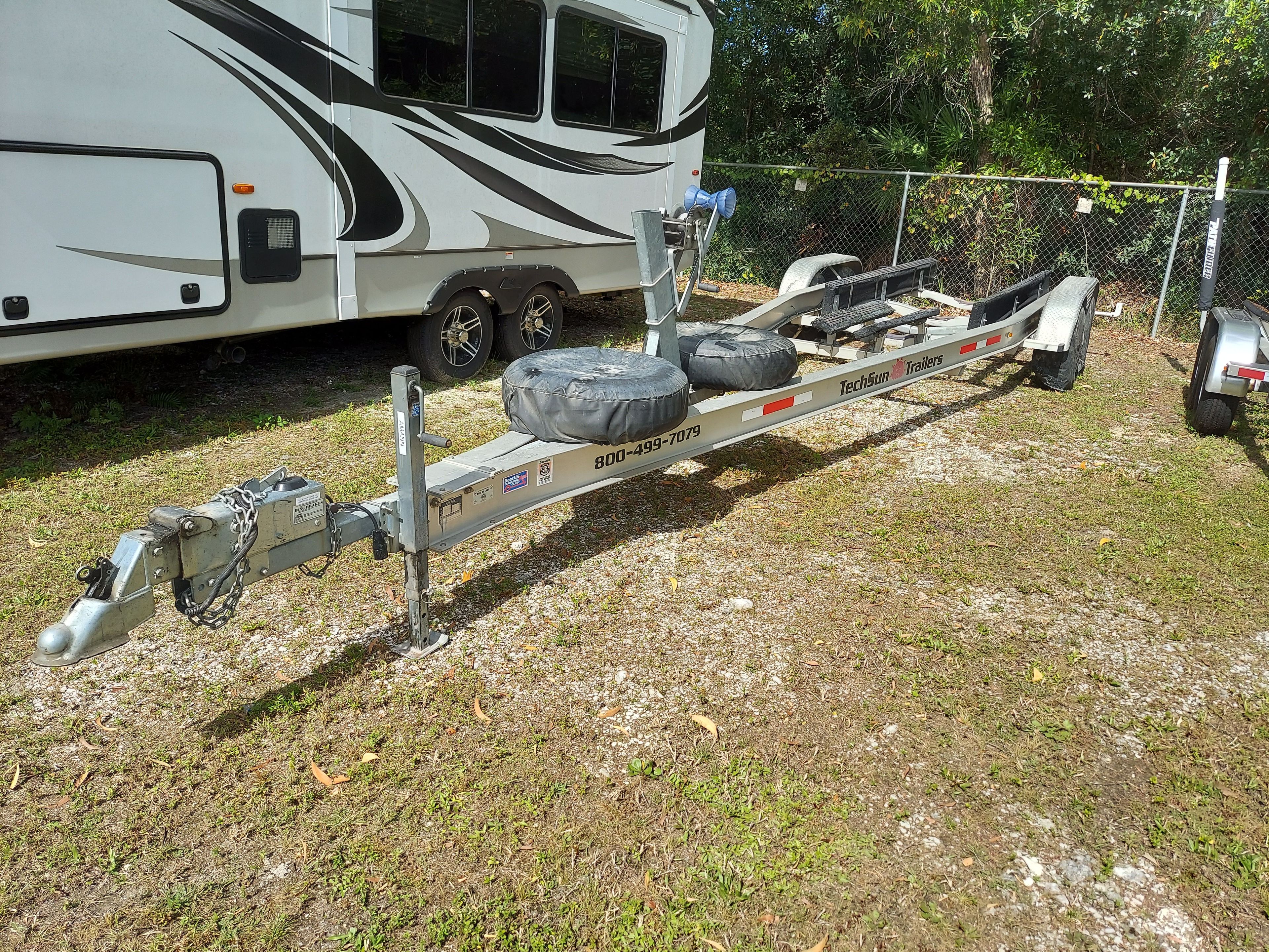 Boat trailer on grass next to an RV.