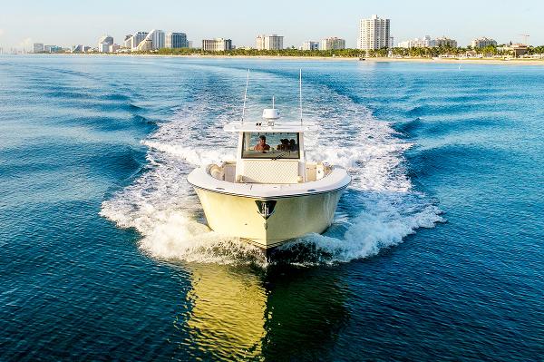 2019 Altima 38 Xcape boat cruising on blue water near city skyline.