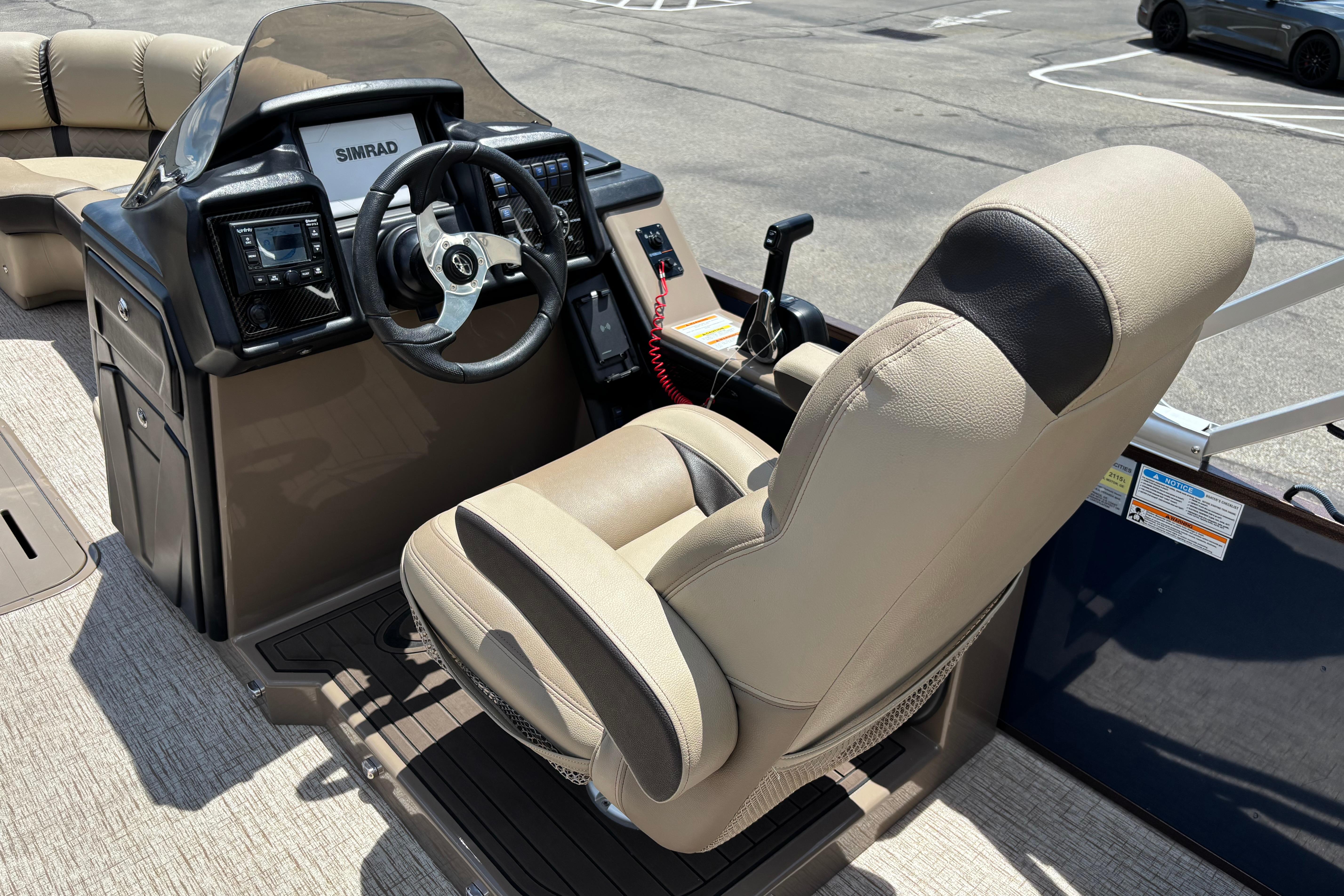 Captain's seat and helm of 2021 Veranda VP25RC pontoon boat, featuring Simrad electronics.