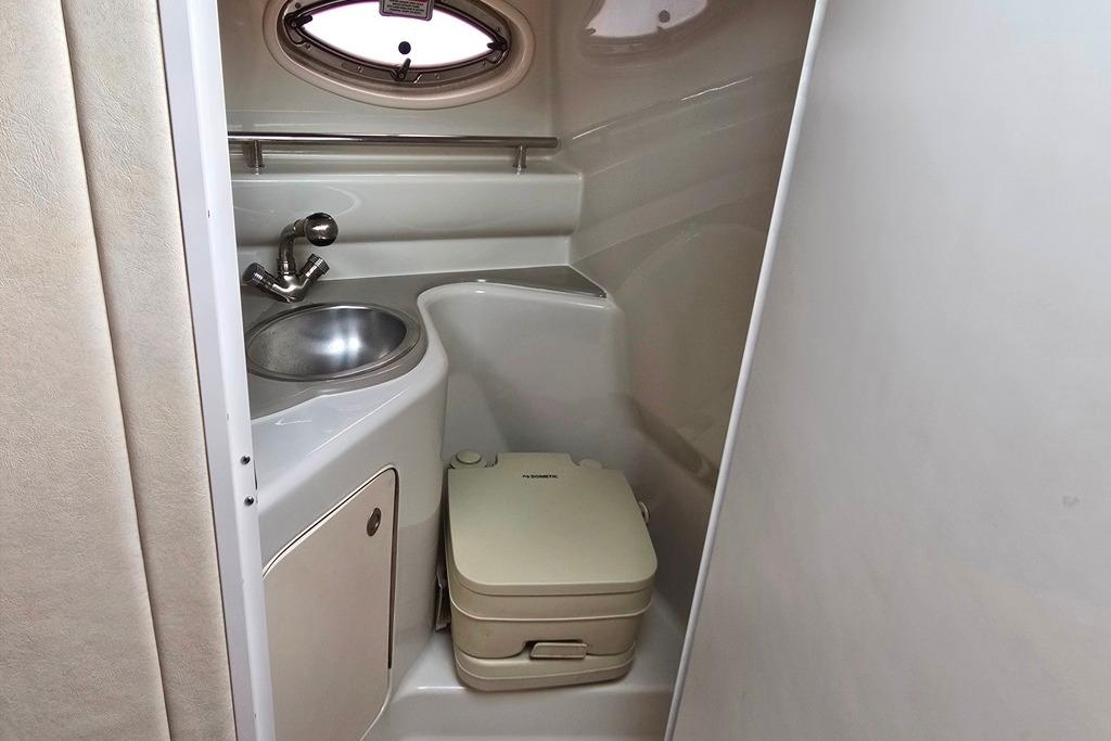 Compact bathroom in 2006 Sea Ray 240 Sundancer boat with sink and portable toilet.