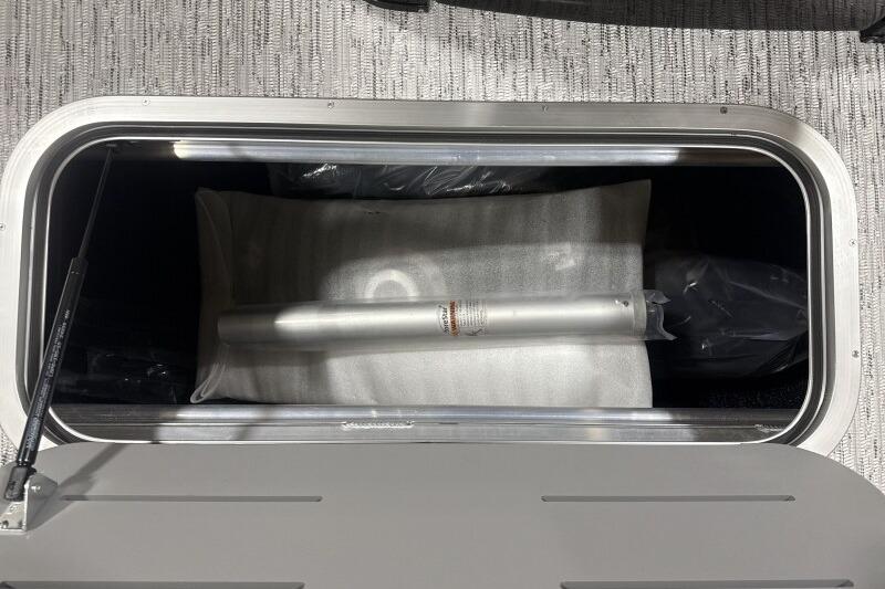 Storage compartment in 2026 Bennington 24 MFBSF boat, featuring a metal rod and cushion.