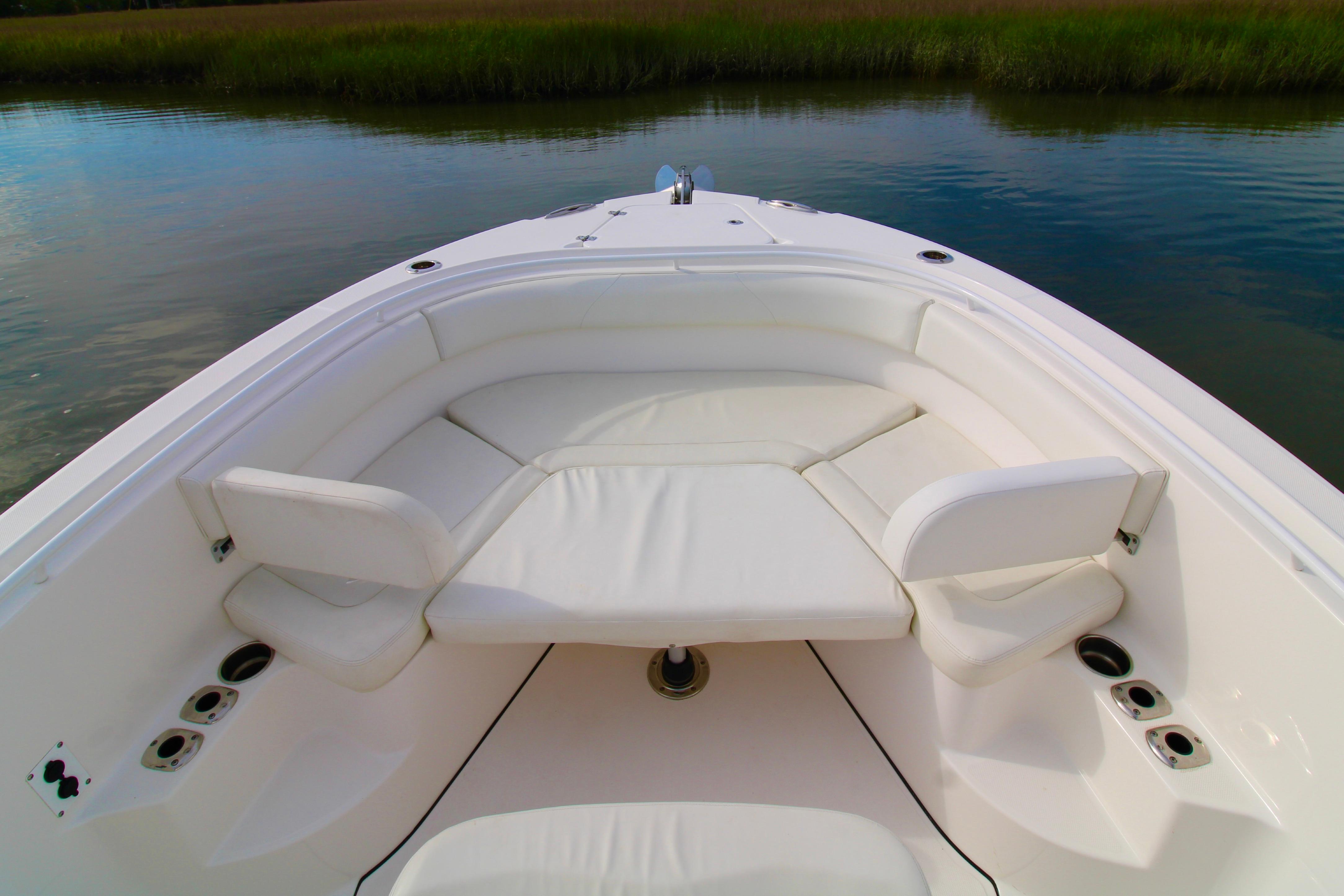 Bow seating area of 2022 Edgewater 280CC boat with white cushions on calm water.
