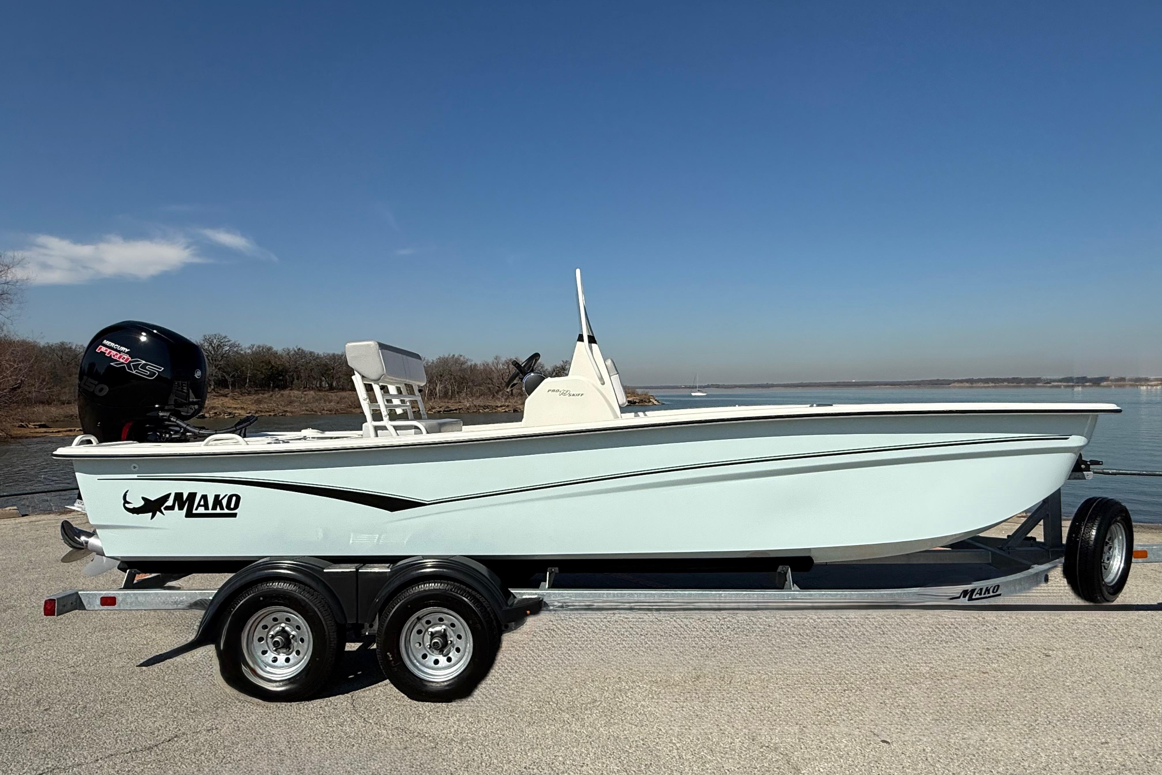 2024 Mako Pro Skiff 19 CC boat on trailer by waterfront under clear sky.
