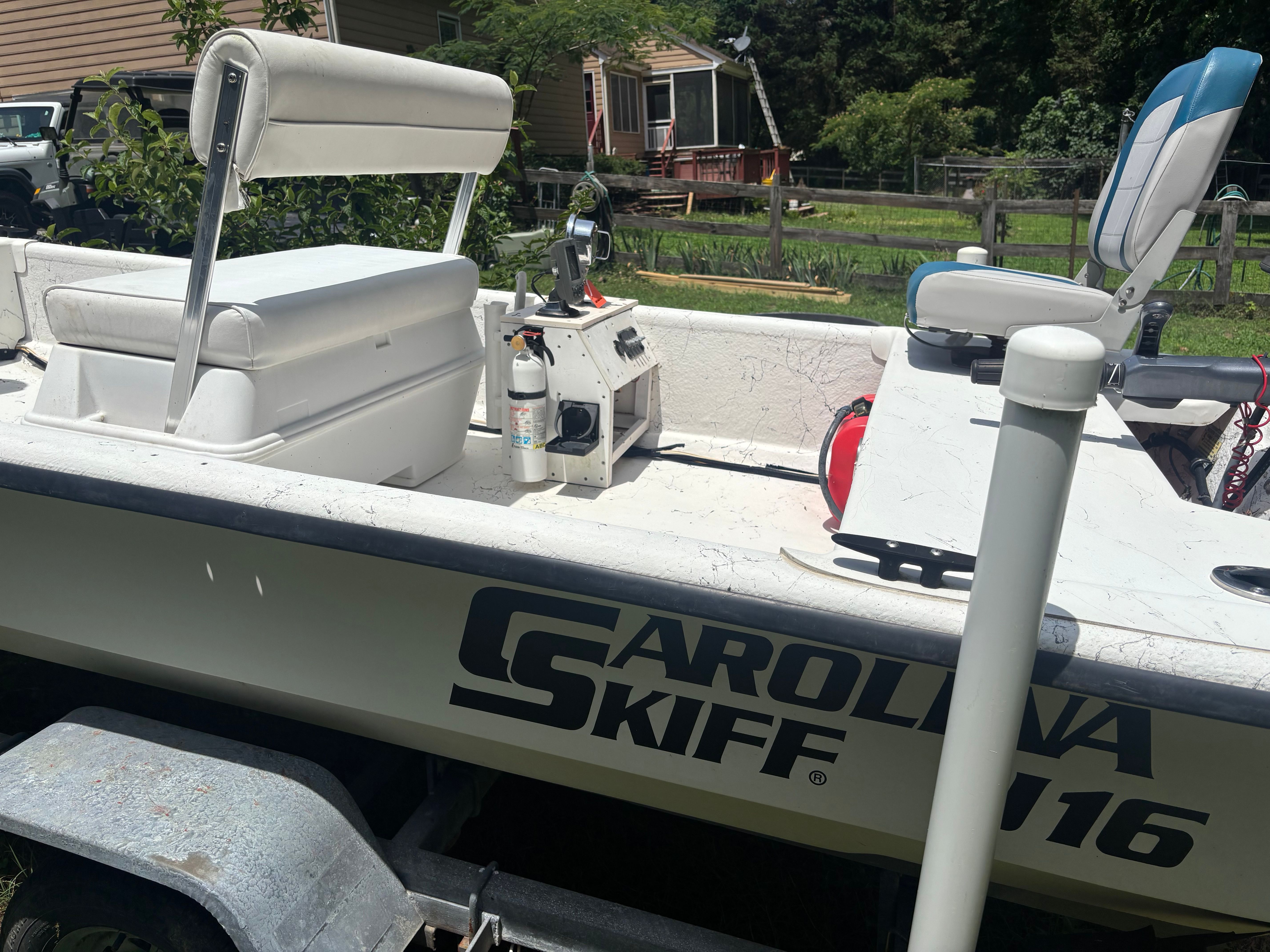 A 2004 Carolina Skiff J16 boat on a trailer in a garden setting.