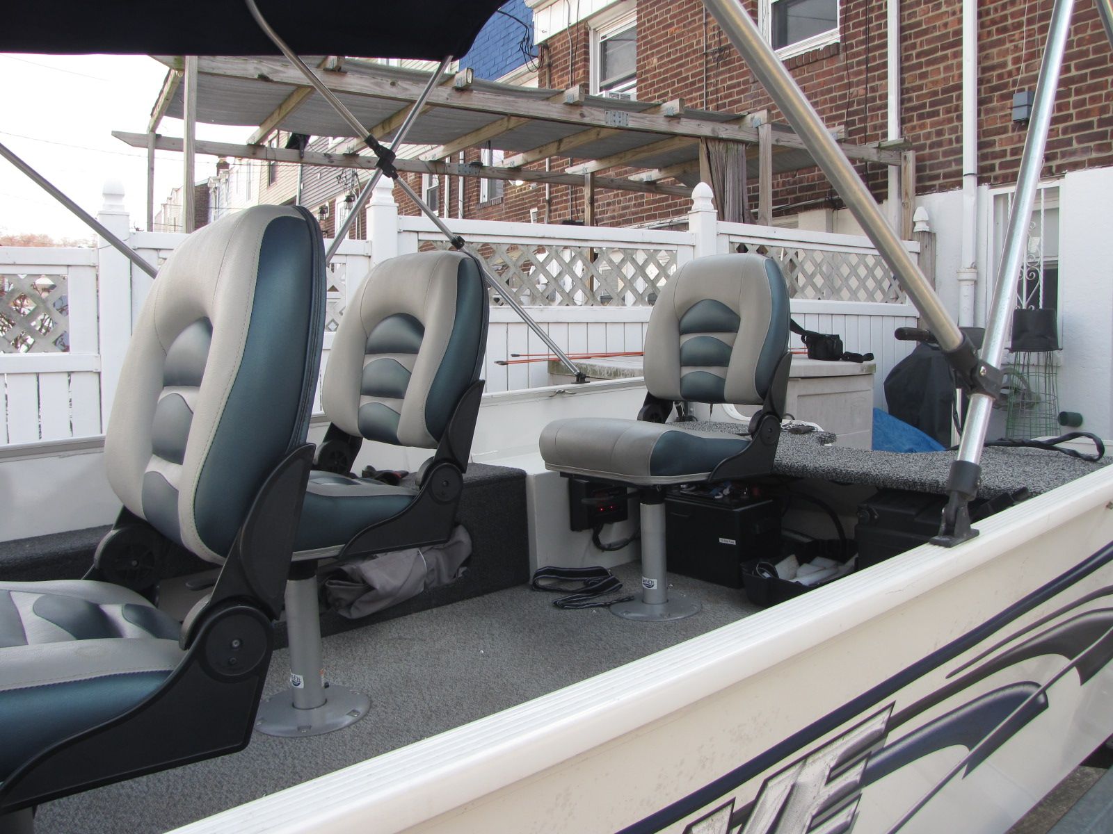 Interior view of a boat with two cushioned seats and a steering console.