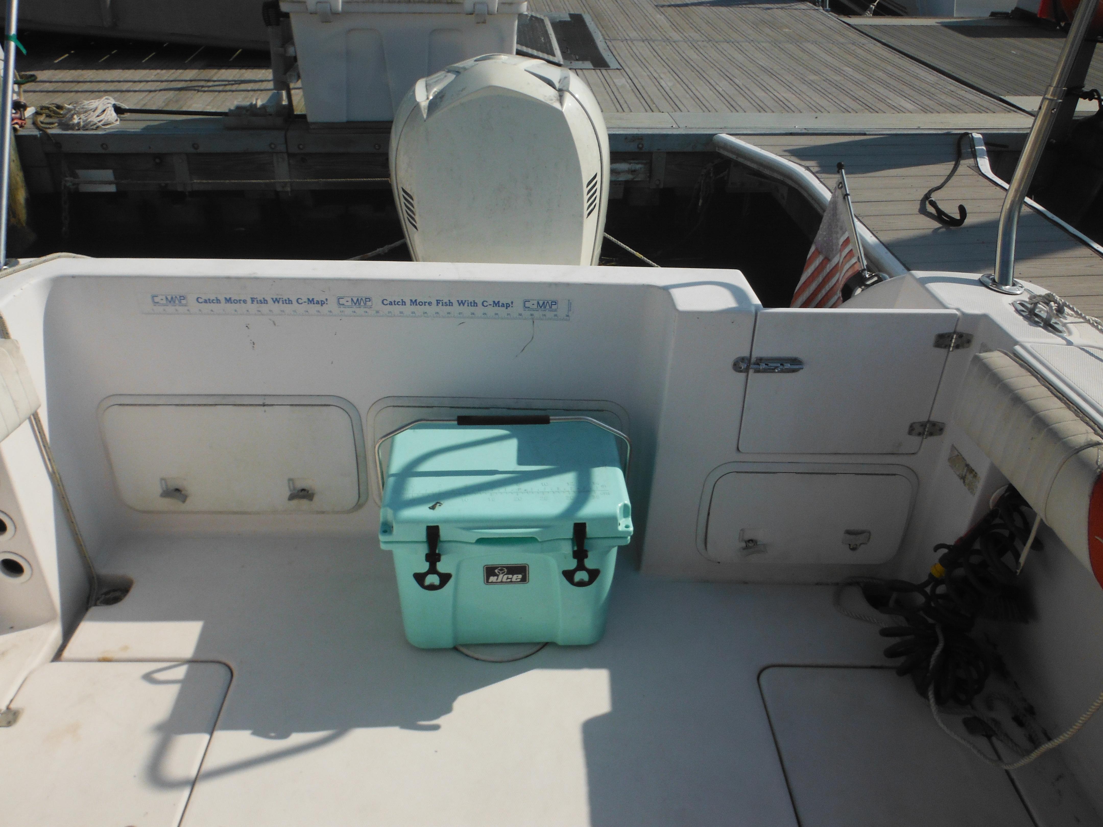 2002 Pro-Line 23 Walk boat deck with cooler and outboard motor.