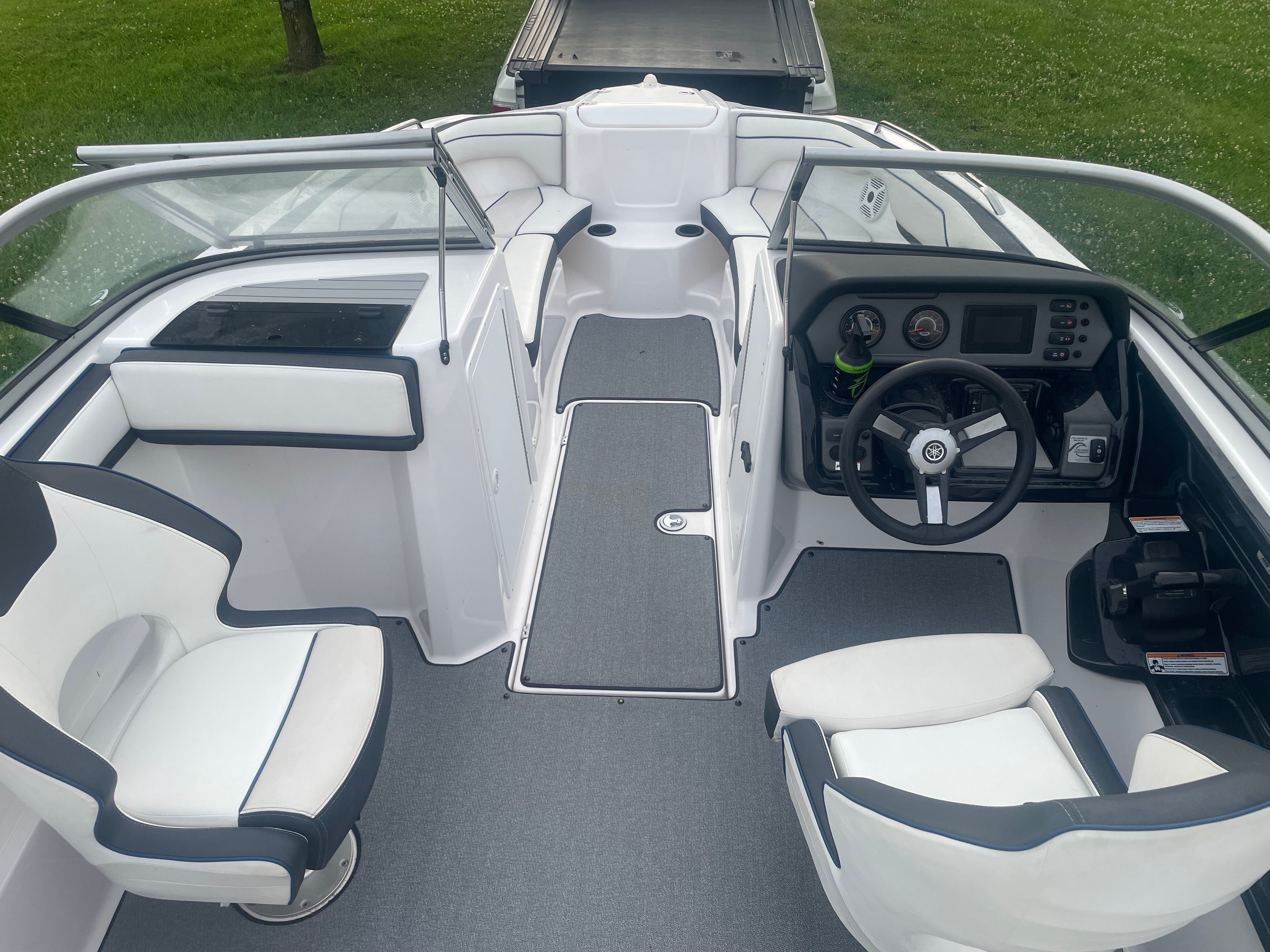 The image shows the cockpit of a 2019 Yamaha SX210 boat with white seats and gray flooring.