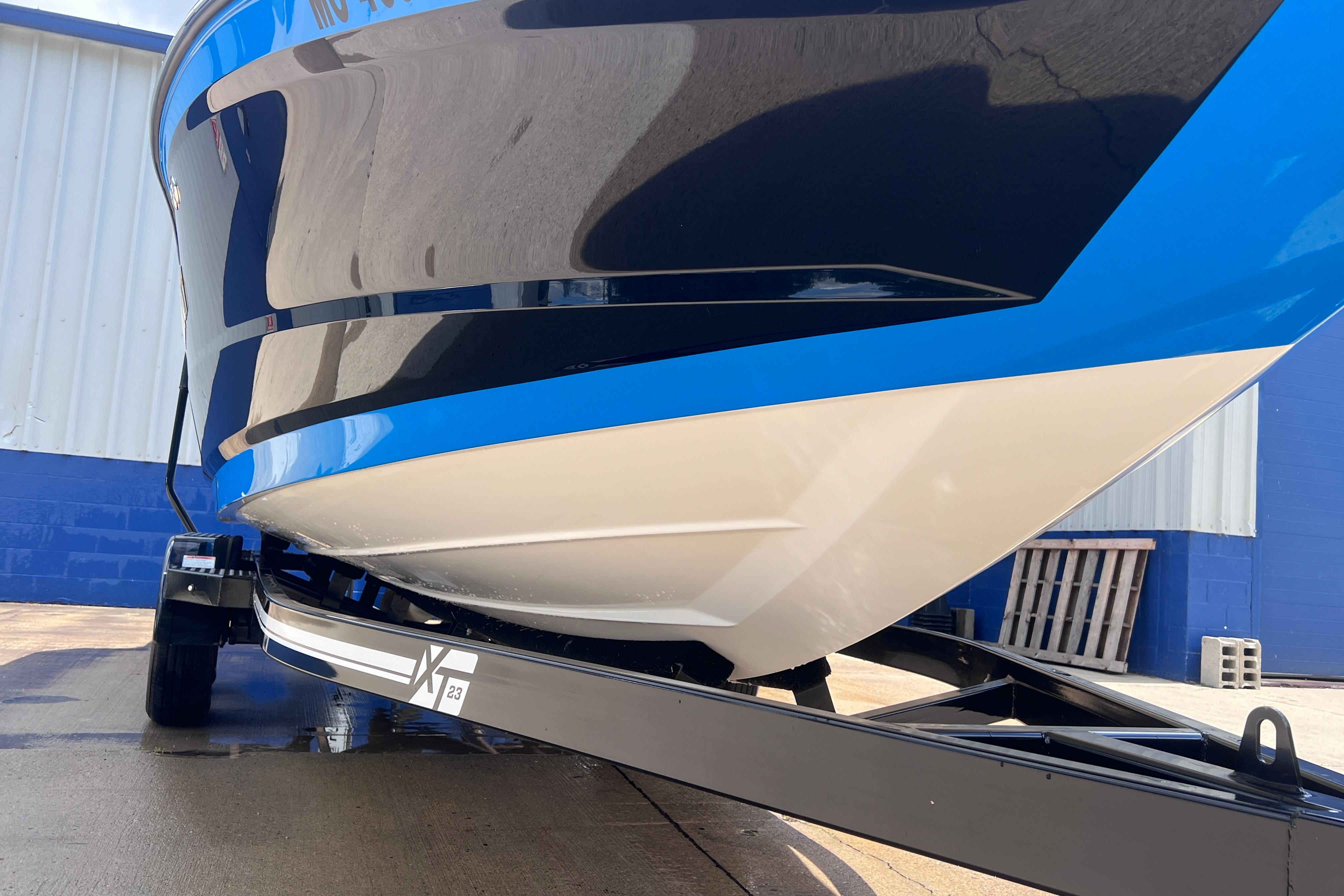 2021 MasterCraft XT23 boat on trailer, blue and white hull, parked outdoors.