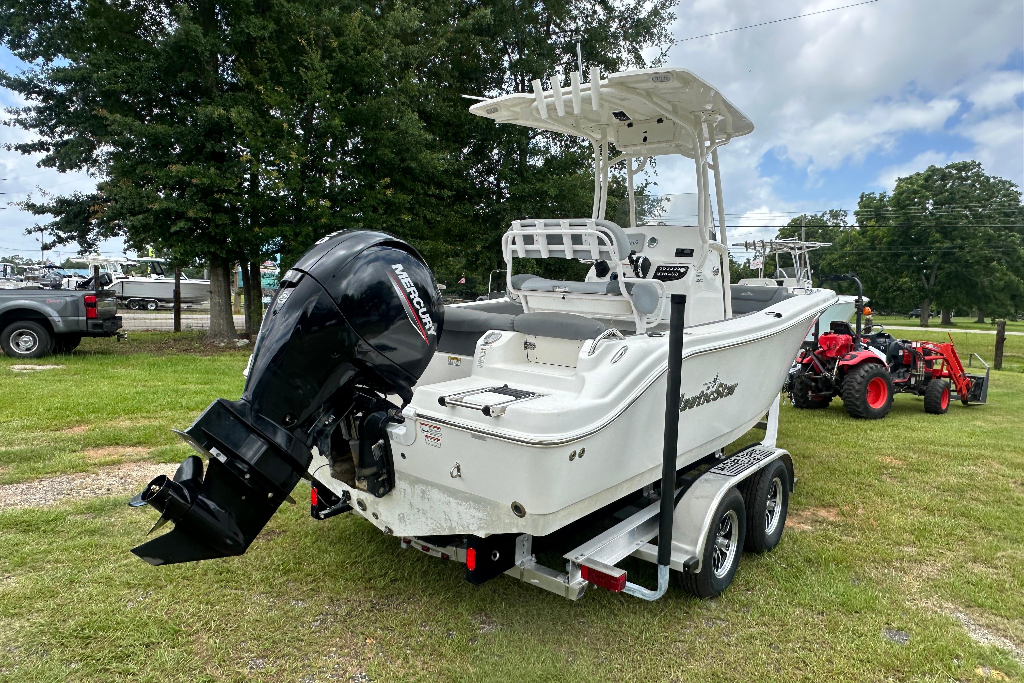 2023 NauticStar 2102 Legacy boat on trailer with Mercury outboard motor, parked on grass.
