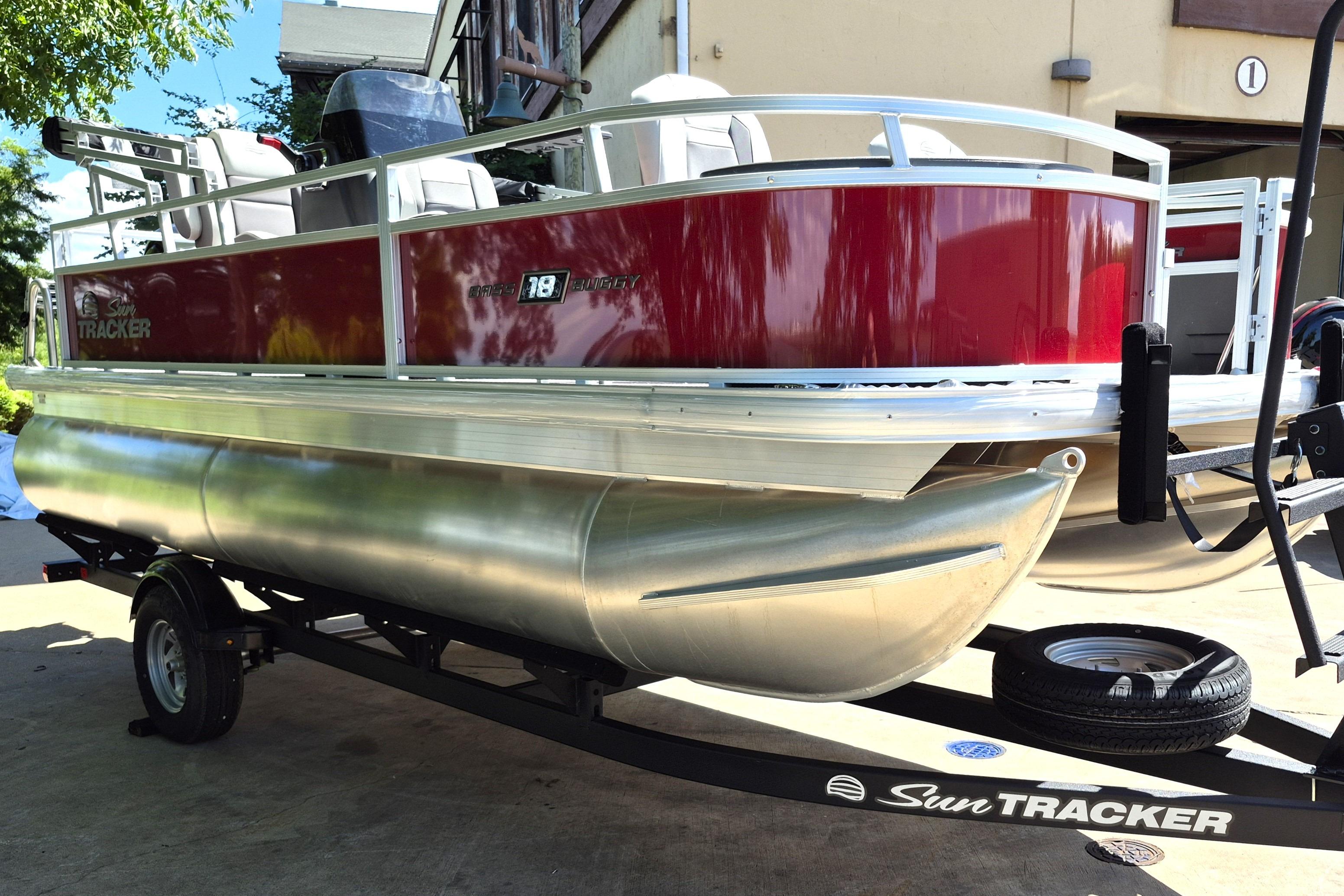 2026 Sun Tracker Bass Buggy 18 DLX pontoon boat on trailer, parked outdoors.