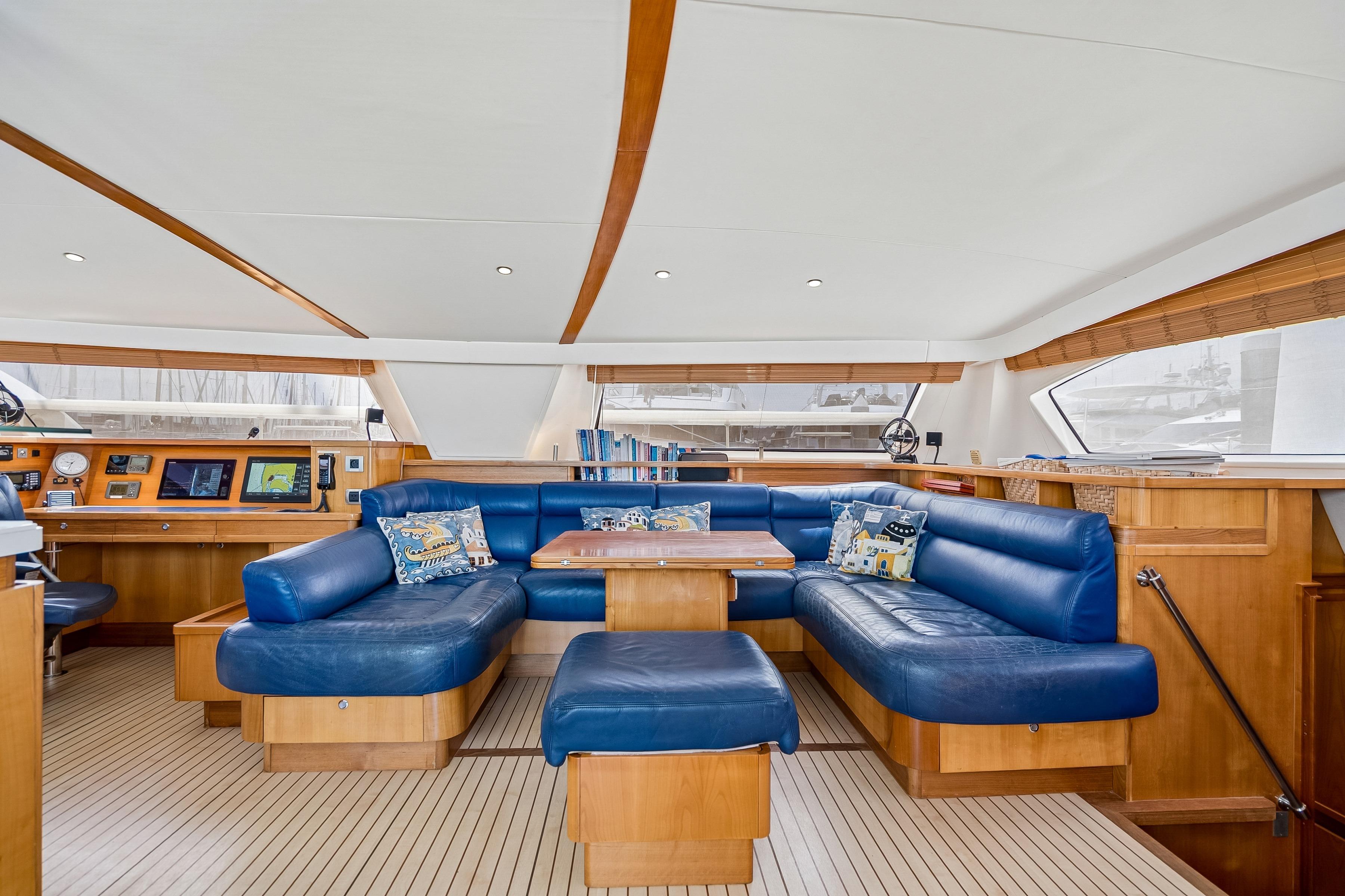 Luxurious interior of 2009 Catana 65 yacht with blue leather seating and wooden accents.