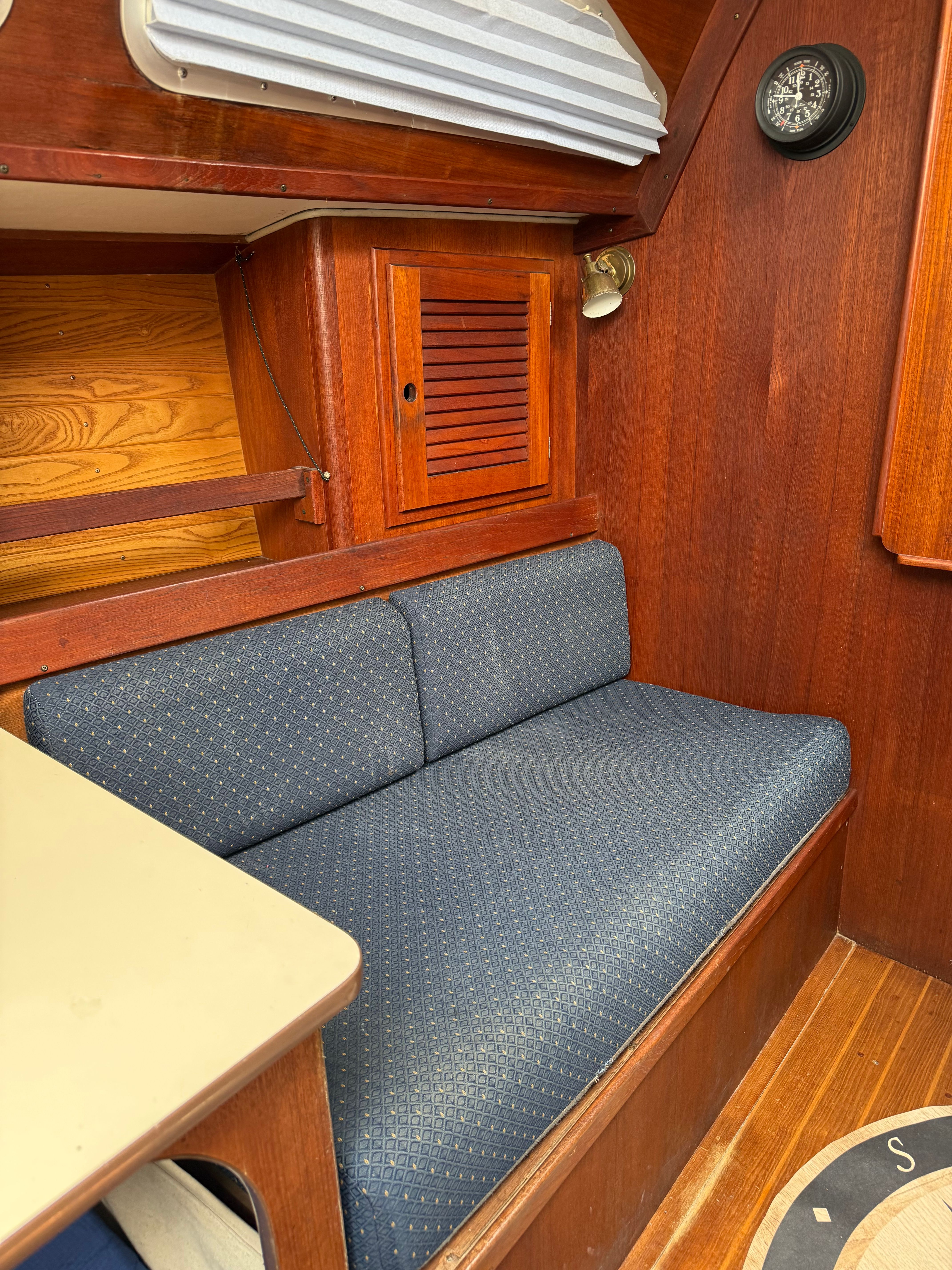 Interior of a sailboat with a blue cushioned bench and wooden walls.