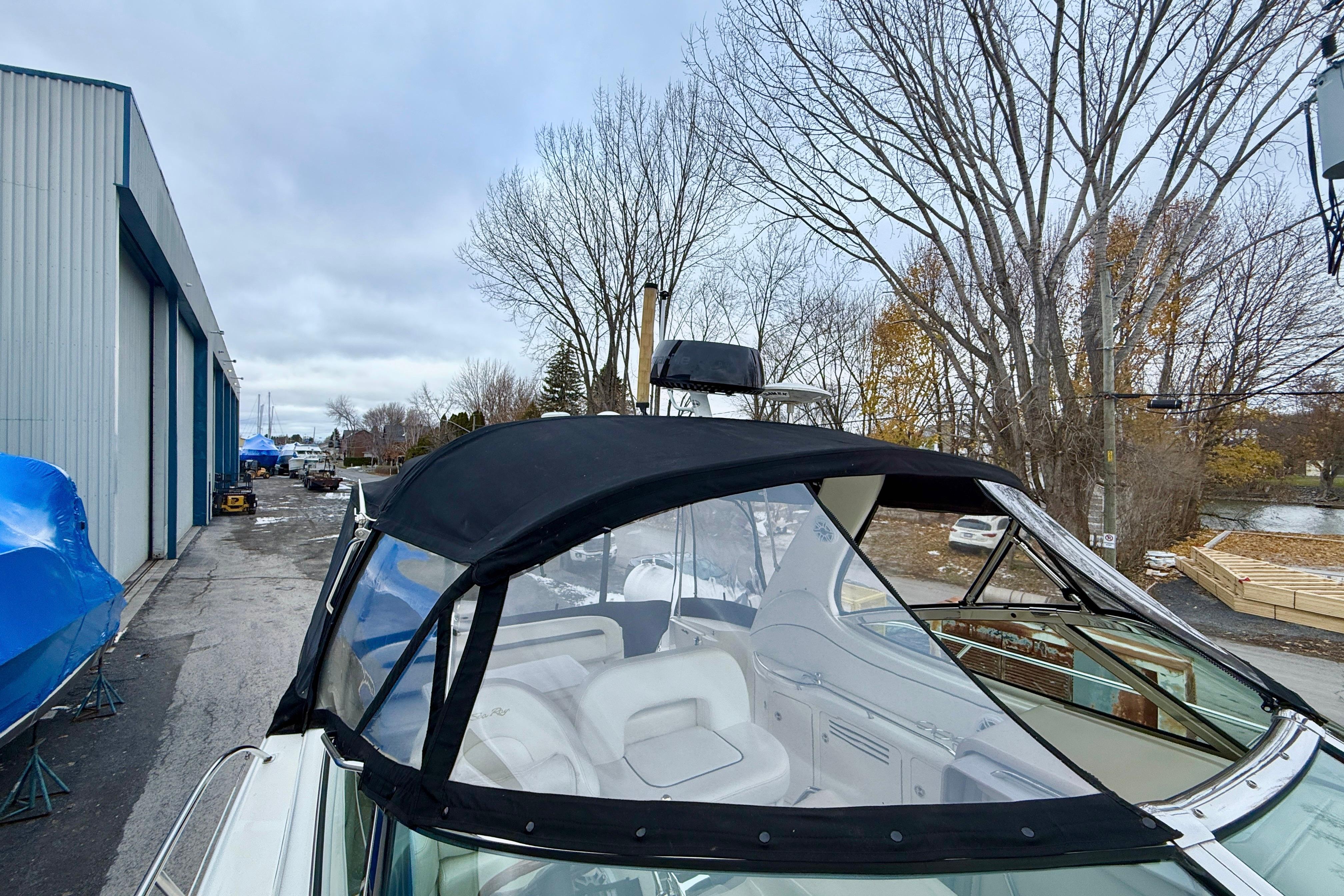 2004 Searay 360 Sundancer boat with black canopy, parked near a storage facility.