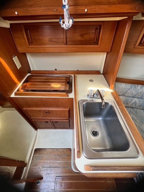 Interior of a 1988 Pearson 28 with a sink and wooden cabinets.