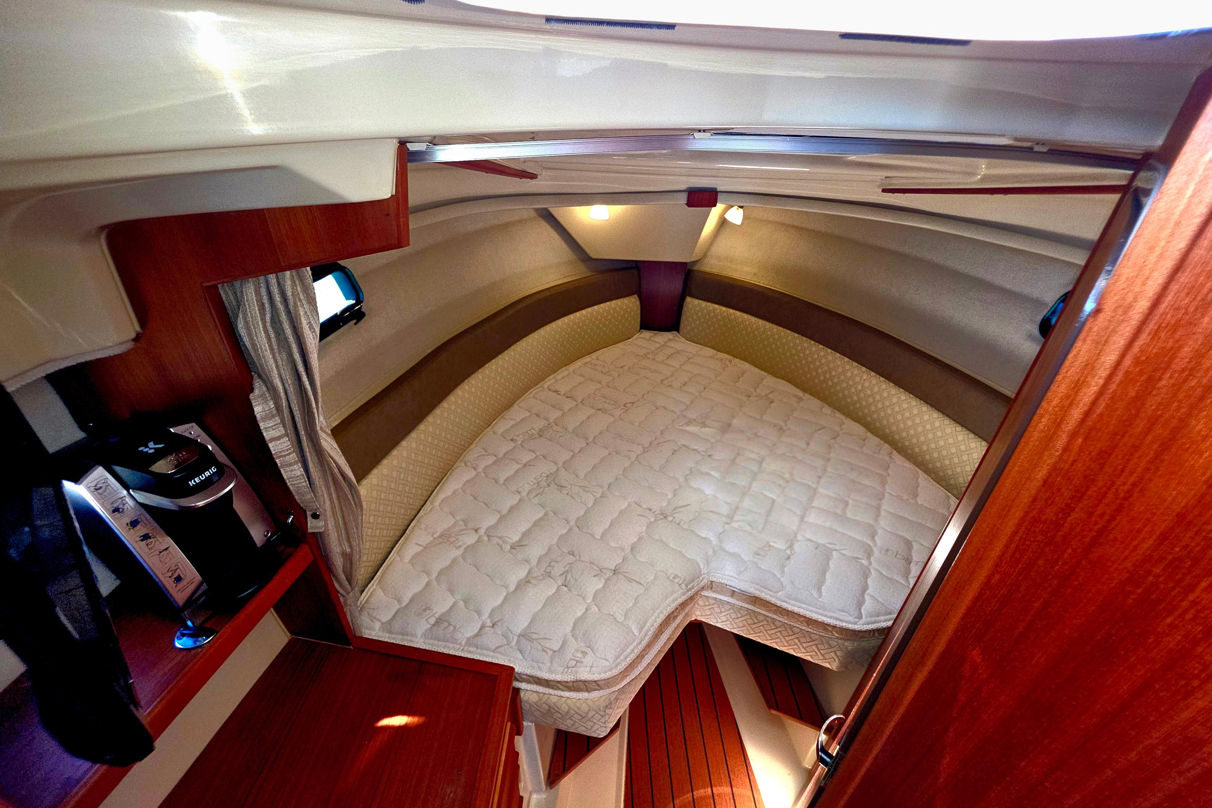 Cozy cabin interior of 2021 Ranger Tug R27 with a comfortable bed and wooden accents.