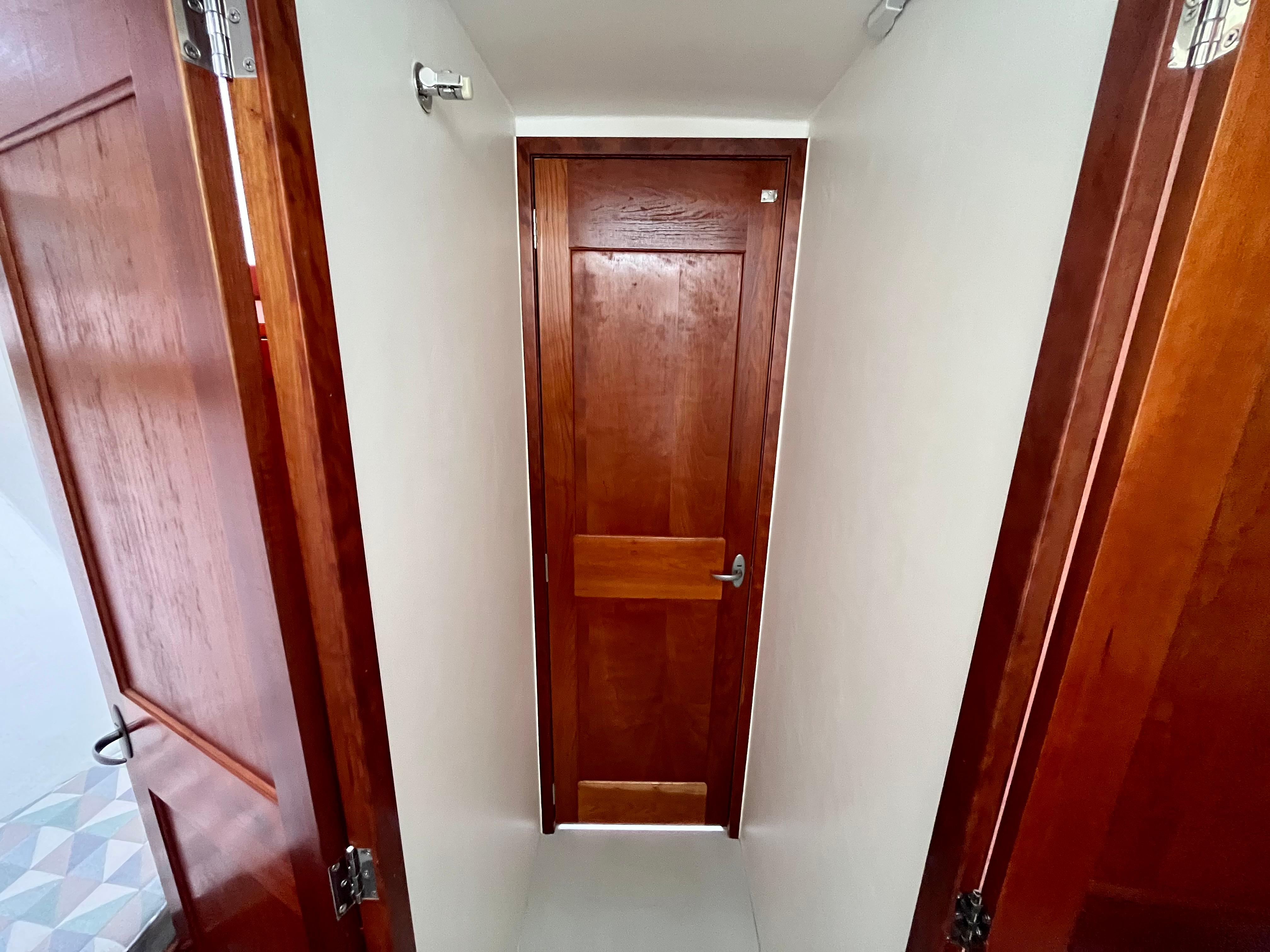 Wooden interior hallway of 2016 Wesmac 42 boat with closed door.