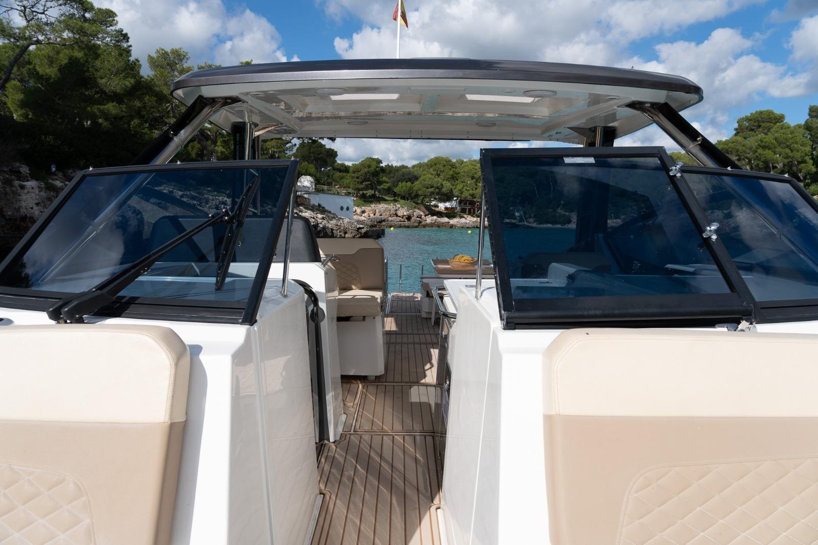 2023 Aquila 32 yacht with open deck, beige seating, and scenic coastal backdrop.
