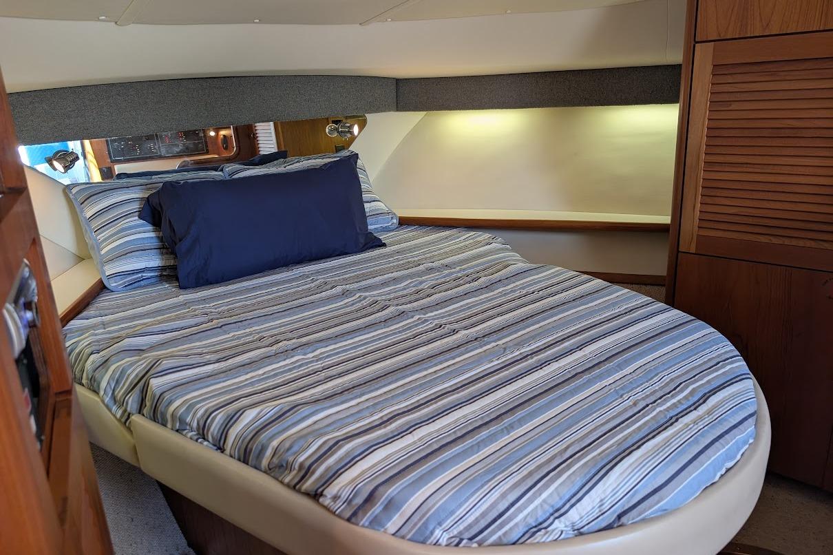 Cozy cabin interior of 2000 Pursuit 3400 Express with striped bedding and wooden accents.