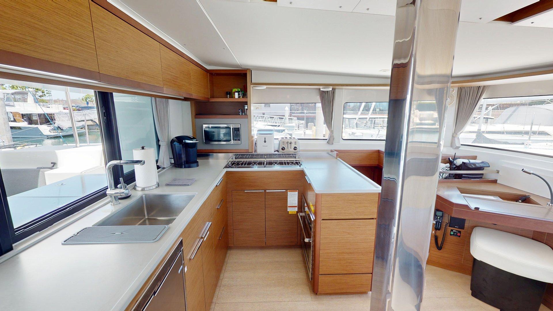 Modern kitchen interior of 2020 Lagoon 46 yacht with wood cabinetry and stainless steel appliances.