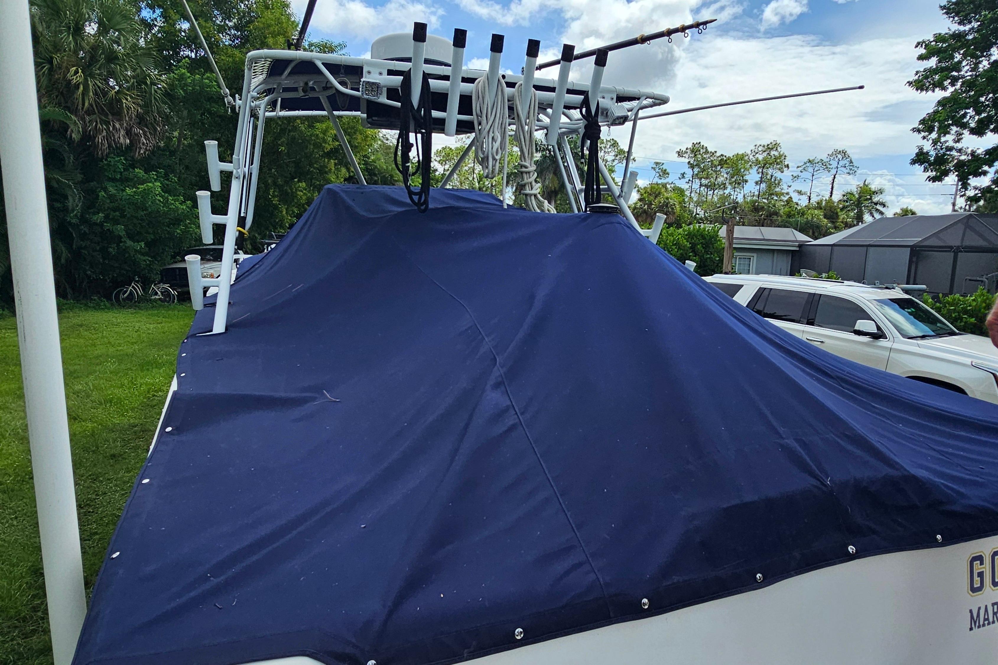 Covered 1993 Marlin 350 Sportfish boat with fishing rods, parked on grass.