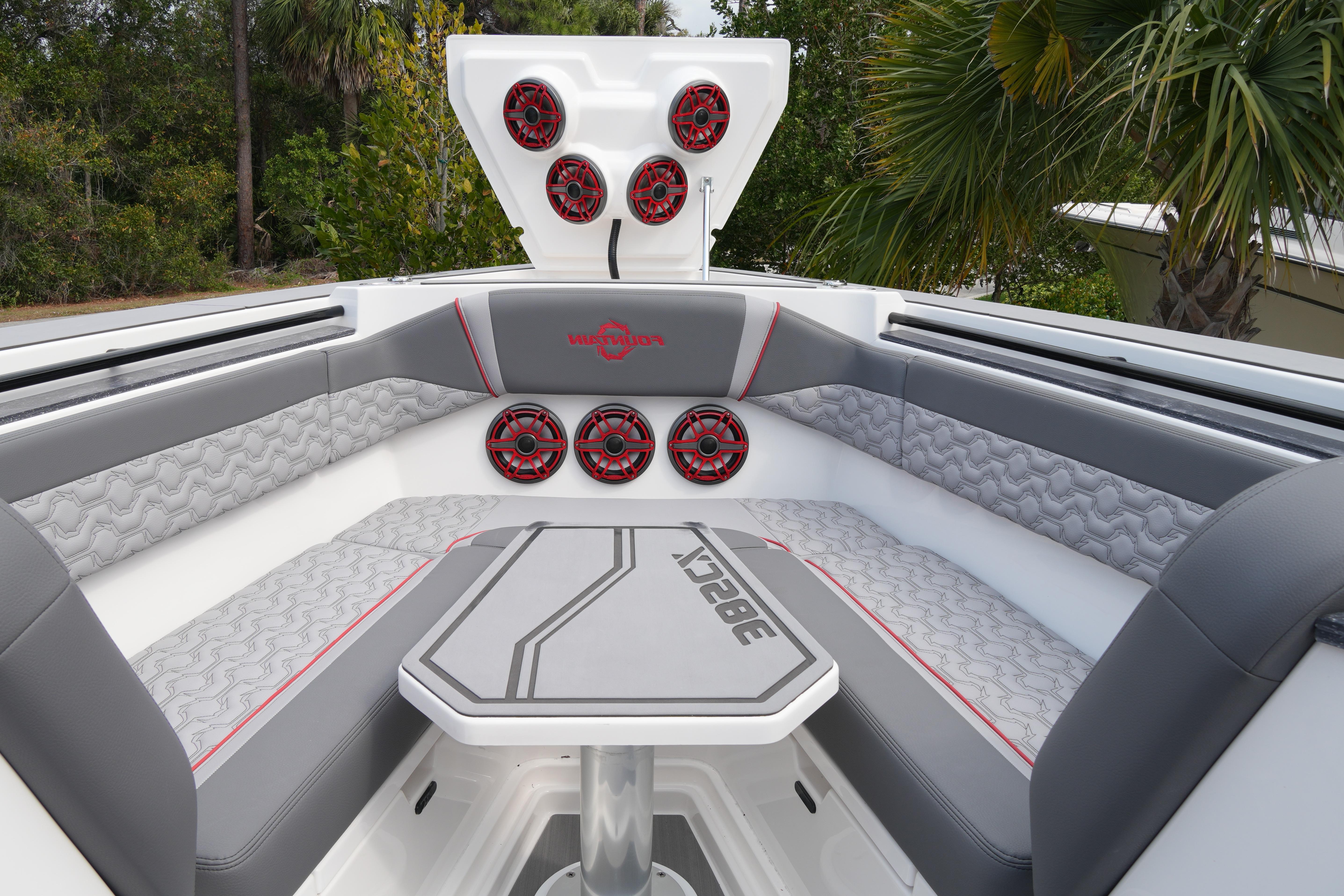 2025 Fountain 38 SCX boat interior with gray seating, red speakers, and a central table.
