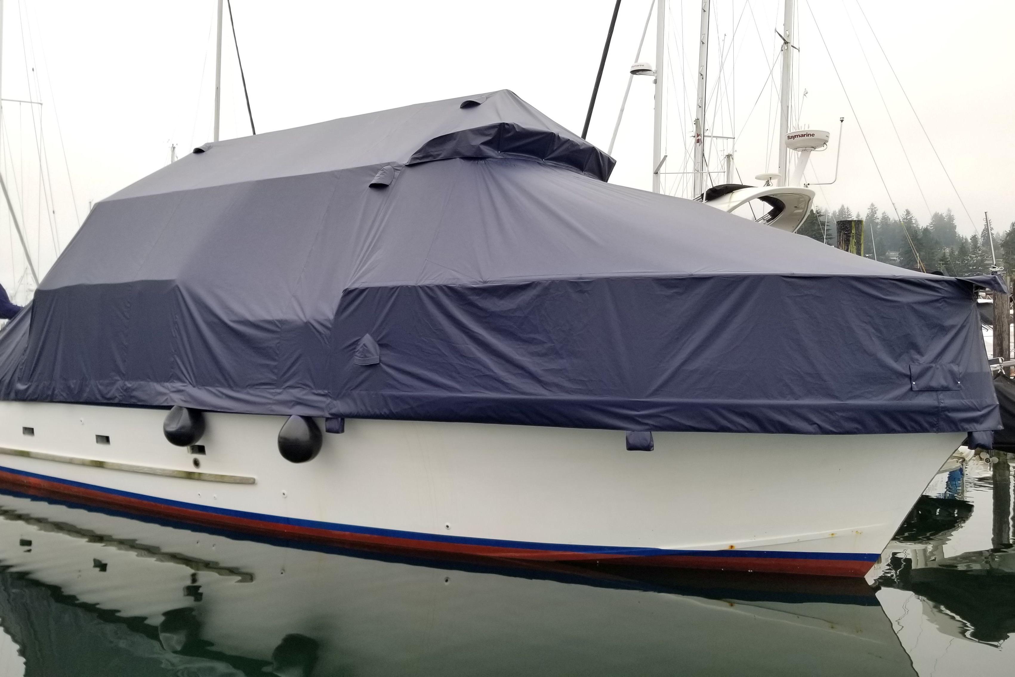1964 Grandy Tour Boat covered with a protective tarp, docked in a marina.