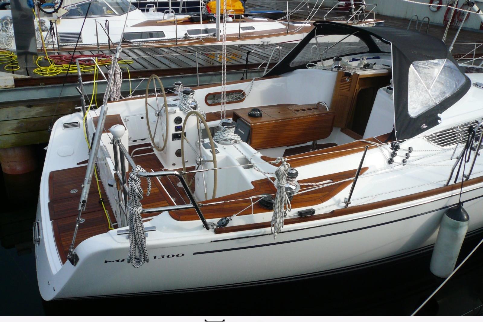 Sailboat Maxi 1300, 2010 model, docked with wooden deck and dual steering wheels.