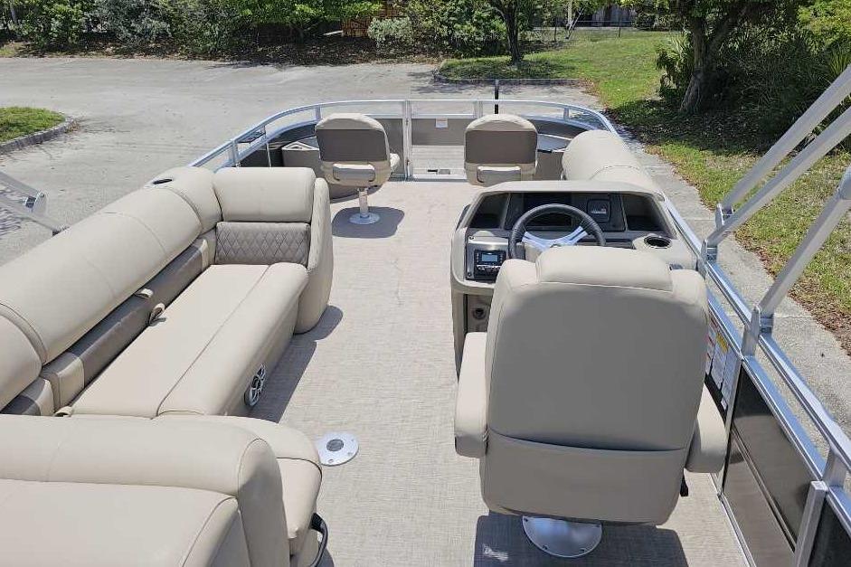 2025 Sun Tracker SportFish 20 DLX pontoon boat interior with beige seating and steering console.
