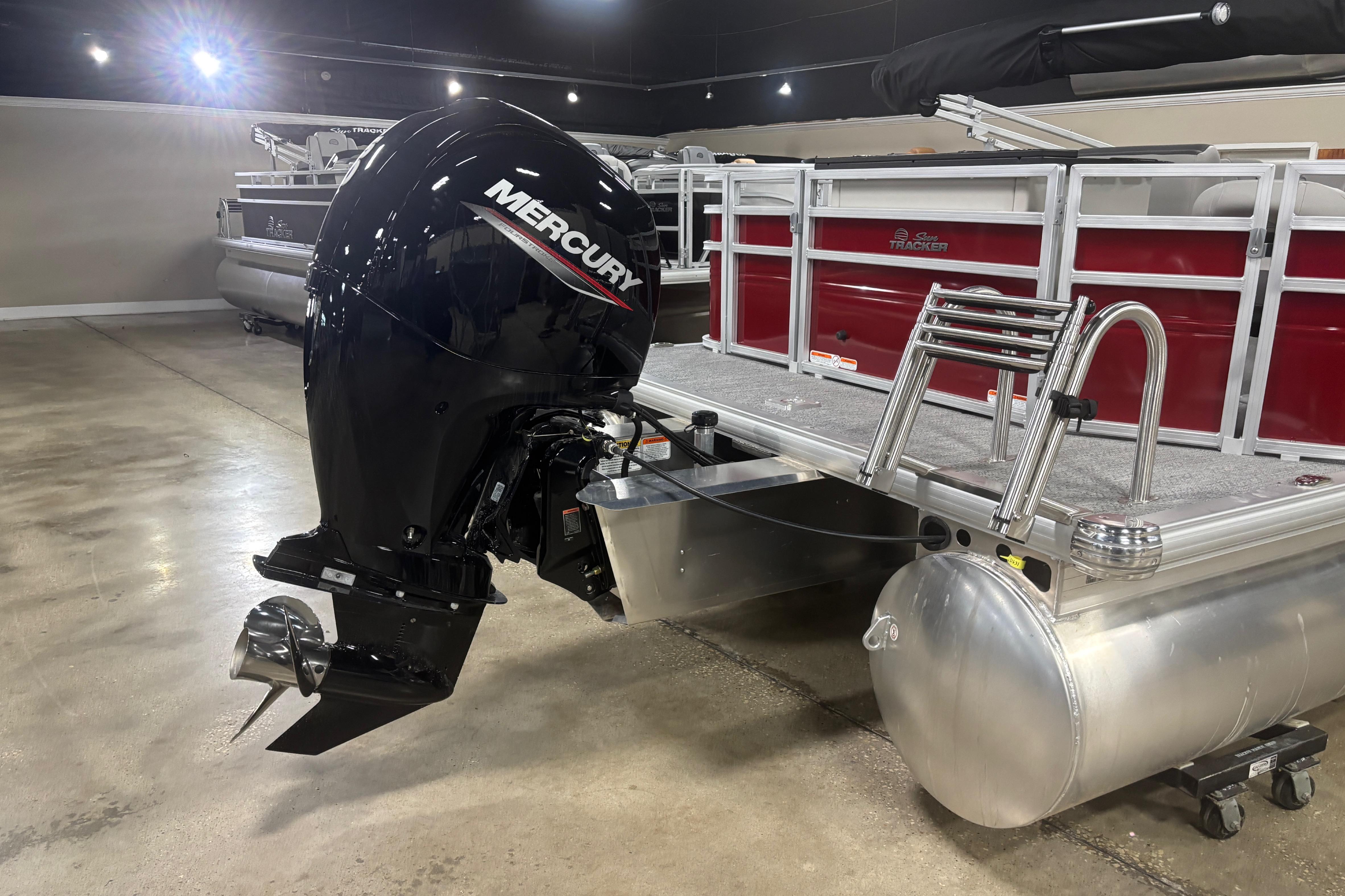 2026 Sun Tracker Fishin' Barge 22 DLX with Mercury outboard motor in showroom.