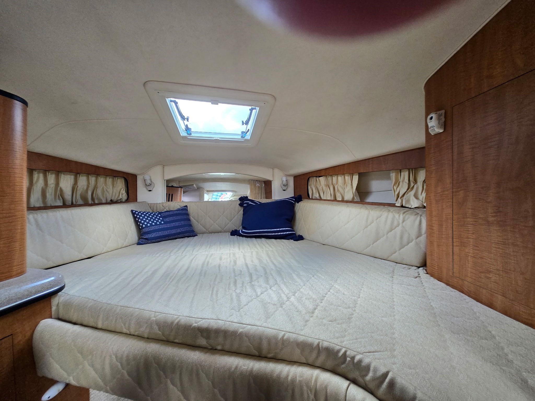 Interior of a 2006 Sea Ray 300 Sundancer with a cozy bed and skylights.