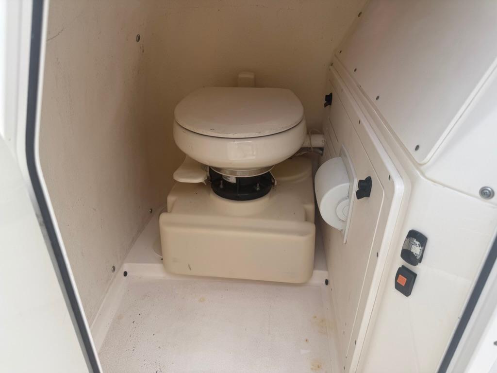 Compact marine toilet inside 2017 ShearWater 270 Carolina Flare boat cabin.