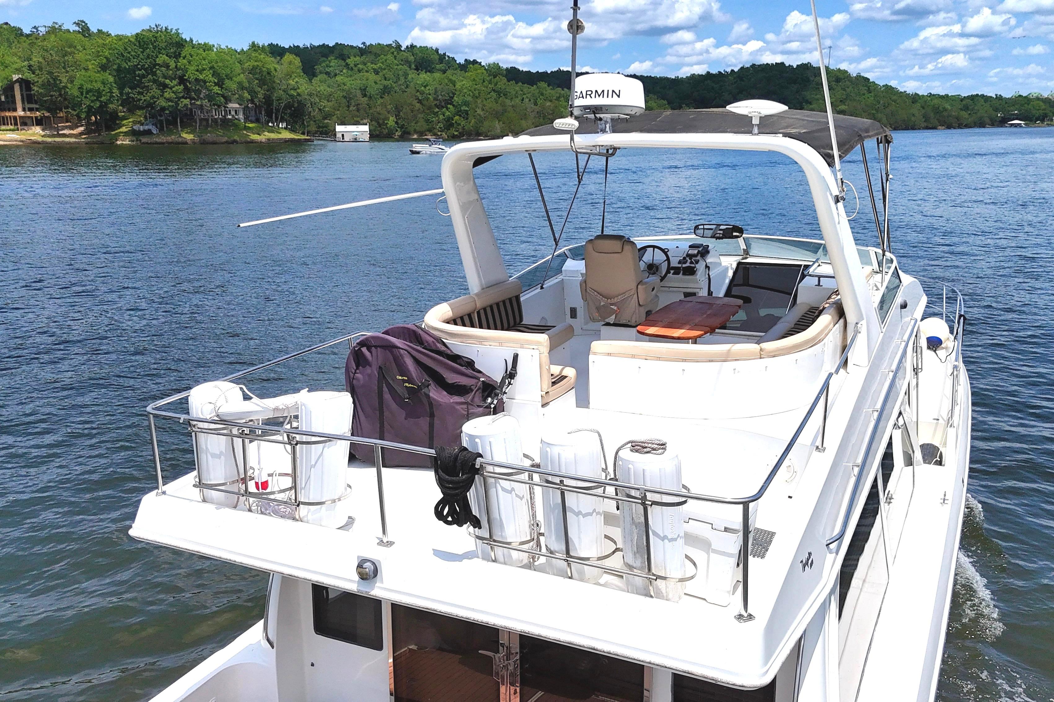 Luxury Navigator 5100 yacht cruising on a serene lake, showcasing spacious deck and seating, 2007 model.