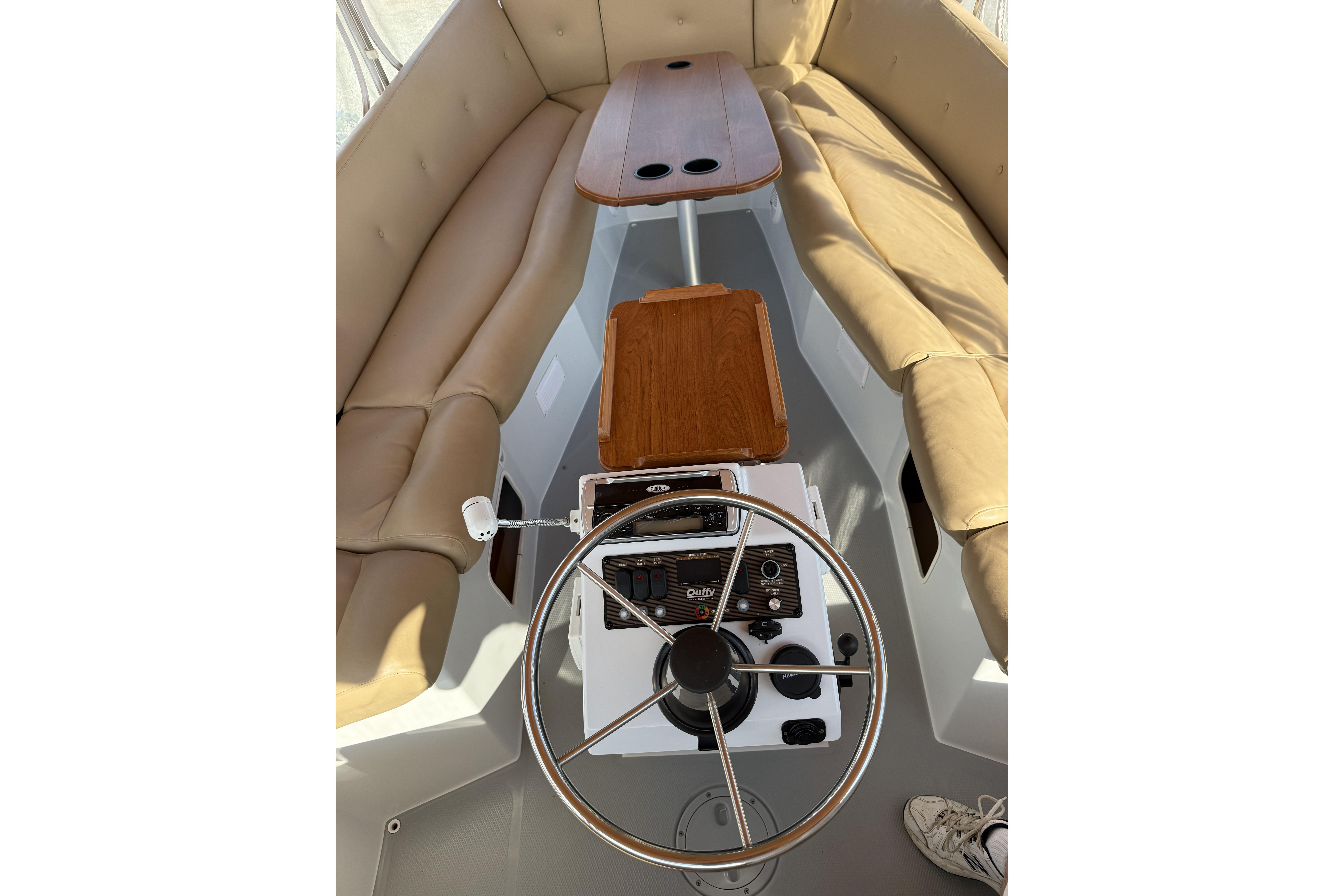 2004 Duffy 21 Classic boat interior with steering wheel, beige seating, and wooden tables.