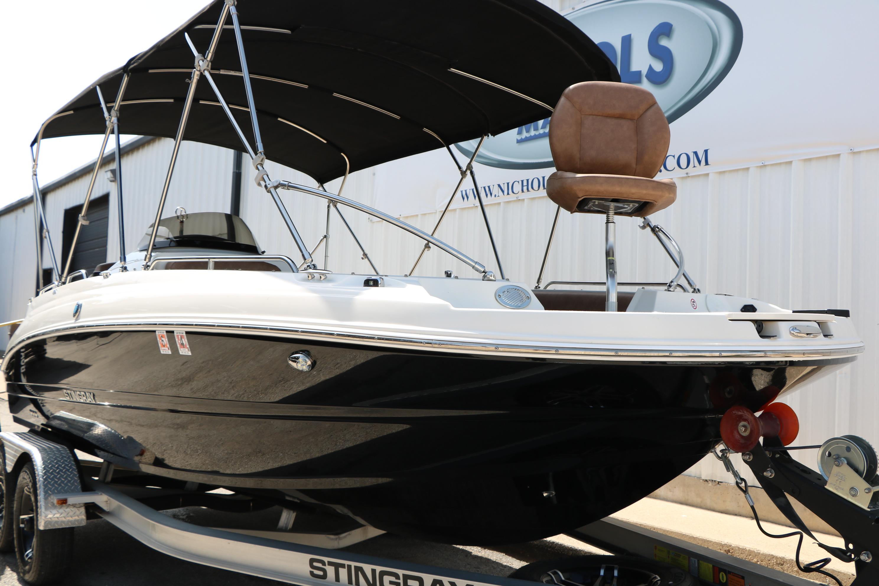 2022 Stingray 192 SC boat on trailer with canopy, parked outside a building.