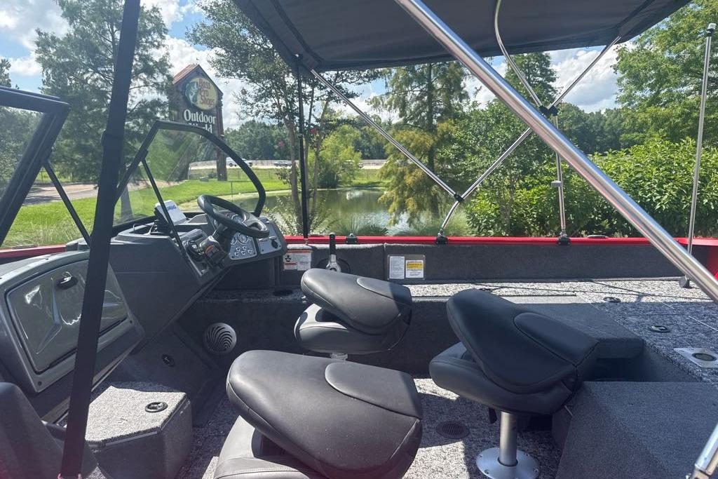 2026 Tracker Pro Guide V-175 Combo boat interior with seating and steering, near a scenic pond.