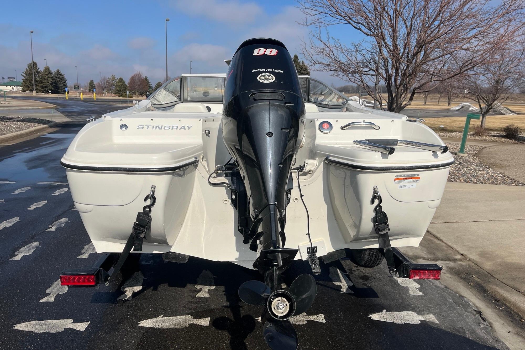 2013 Stingray 191 RX boat with outboard motor, parked on a sunny day.