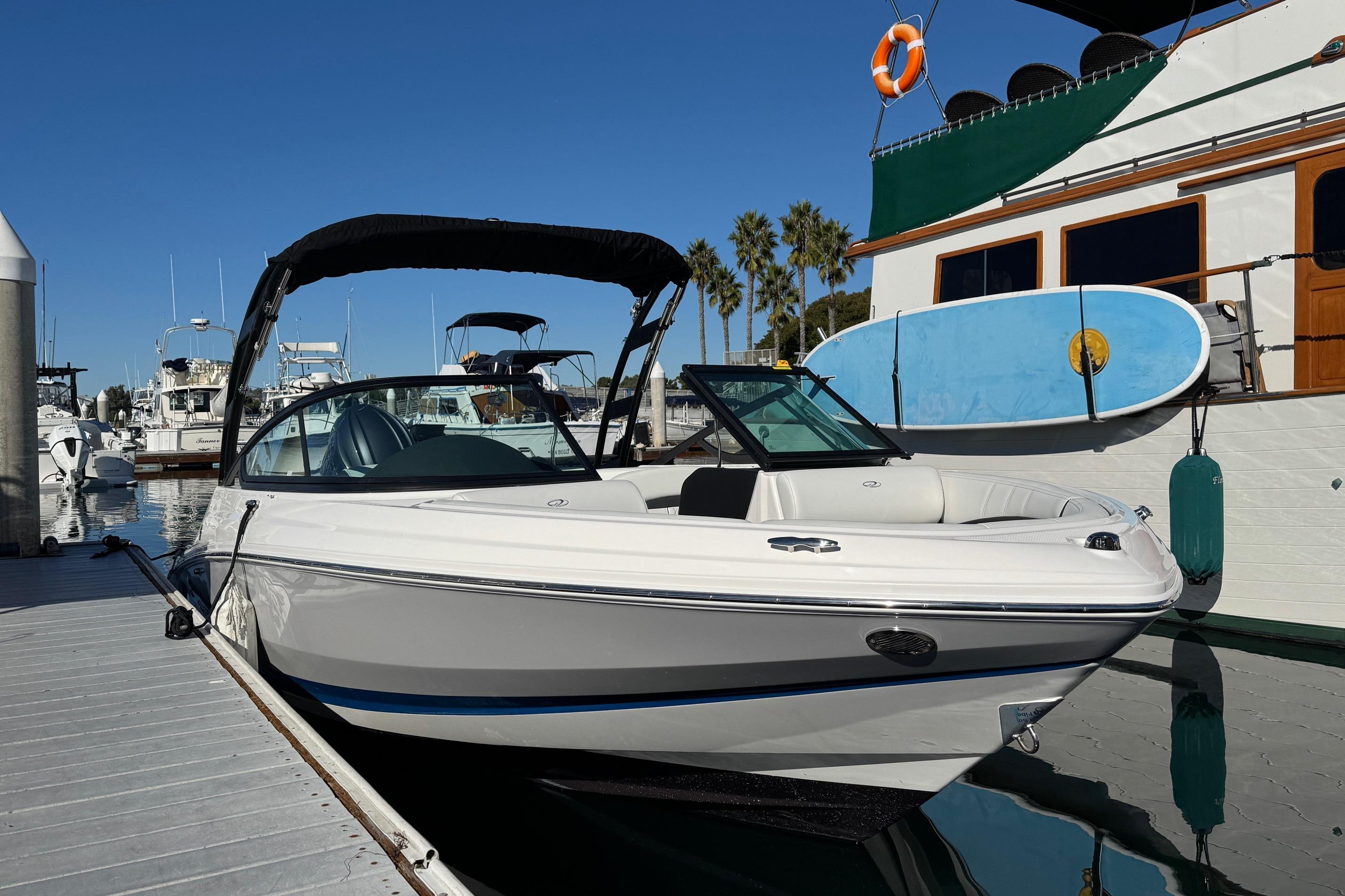 2026 Regal 21 OBX boat docked at marina, clear sky, paddleboard nearby.