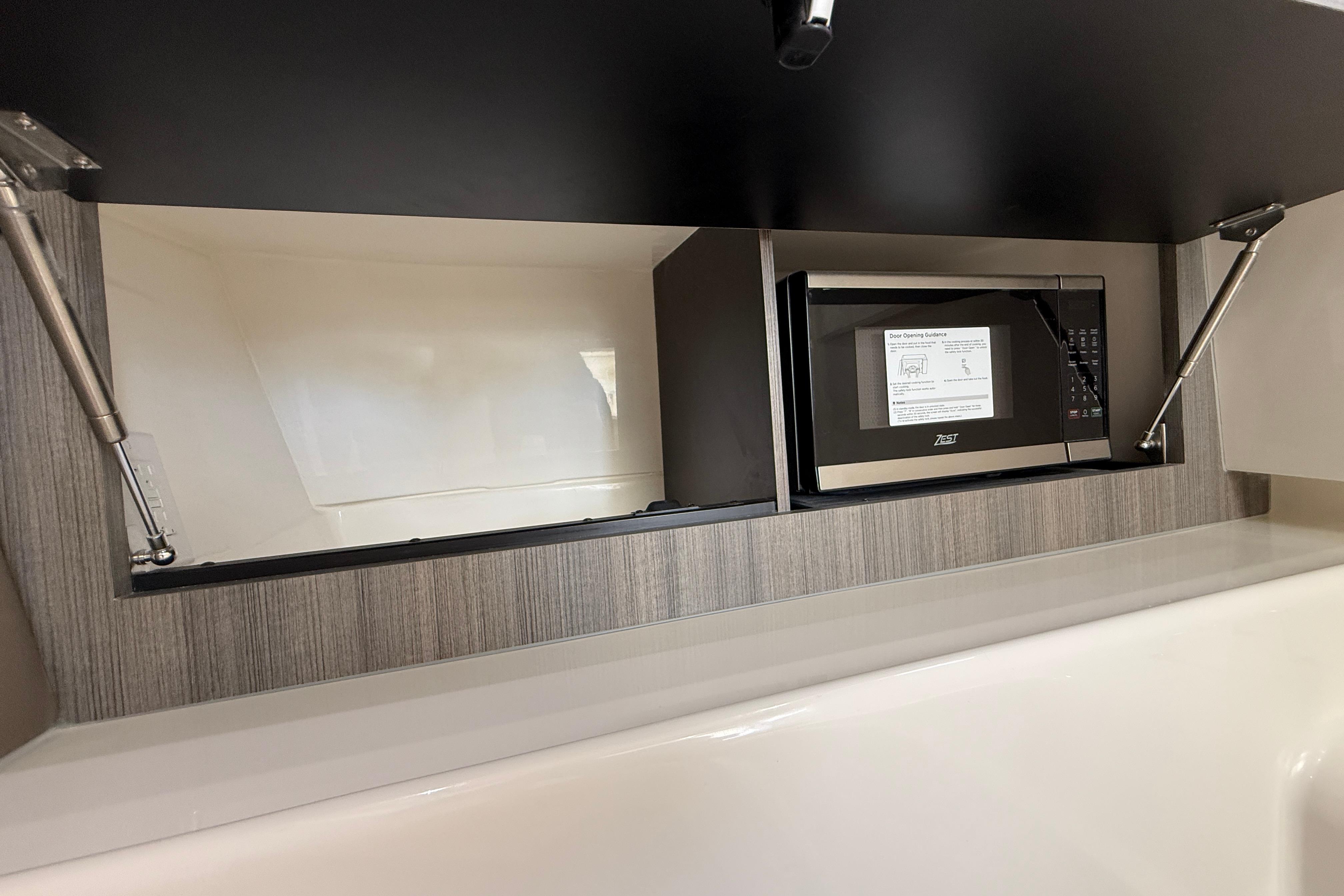 2026 World Cat 400 DC-X Island boat interior with microwave in modern cabinetry.