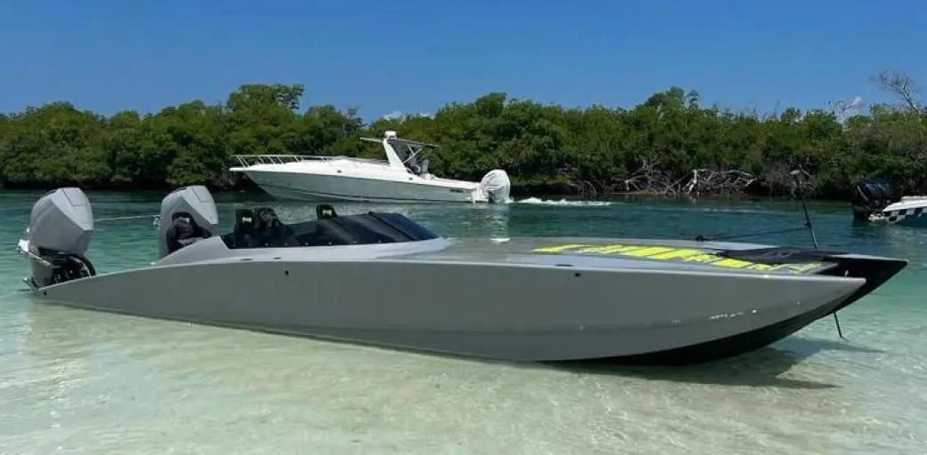 2021 HellKats 320X powerboat on a sandy shore with a scenic background.