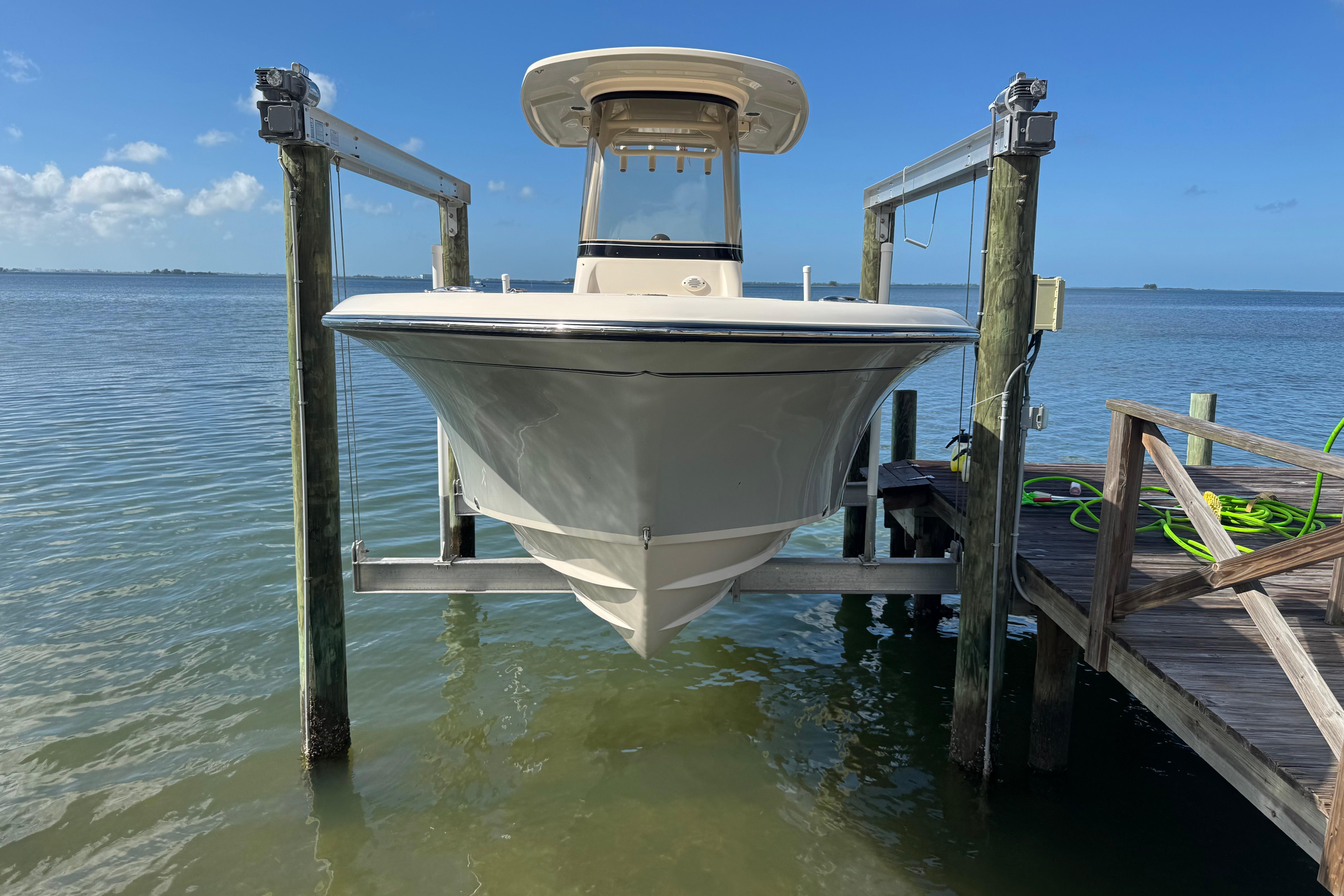 2023 Grady-White Fisherman 236 boat on lift by dock, clear blue sky.