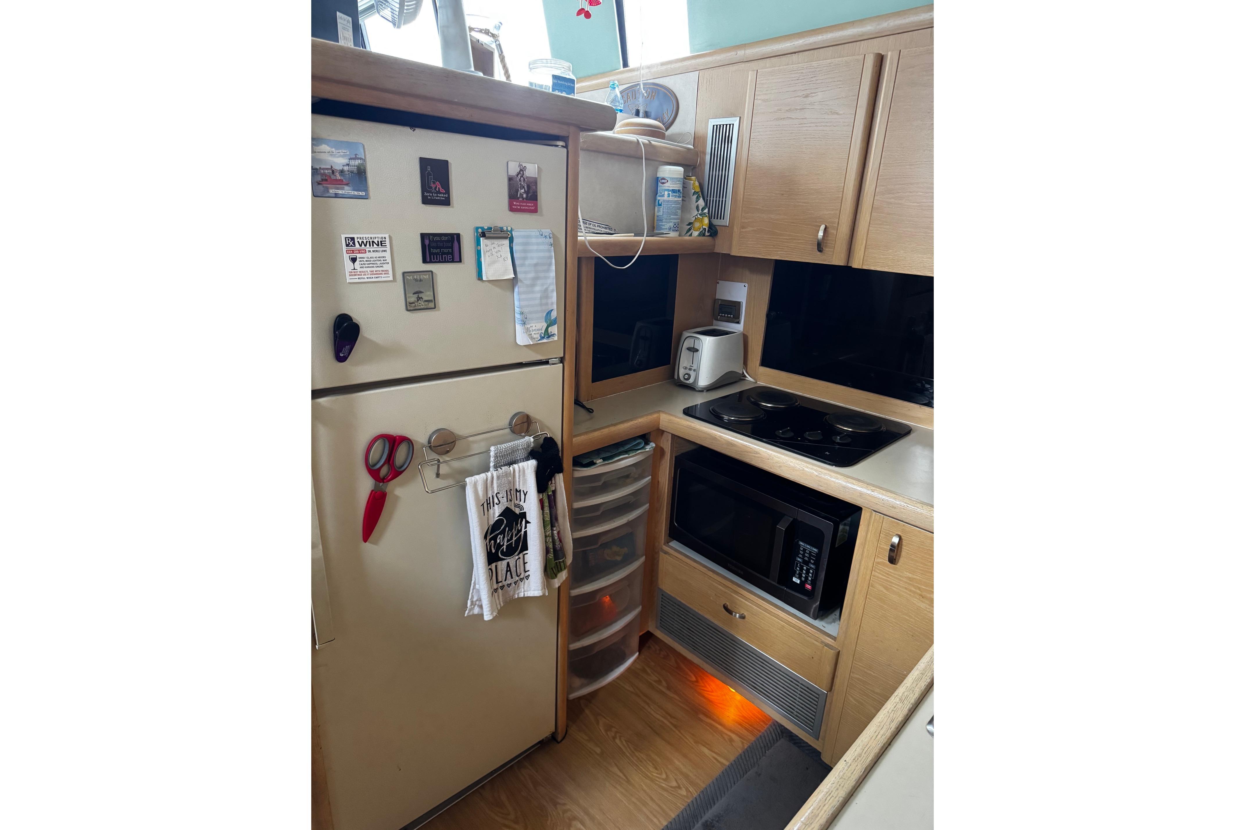 Compact kitchen in a 1991 Silverton 46 Motor Yacht with appliances and wooden cabinetry.