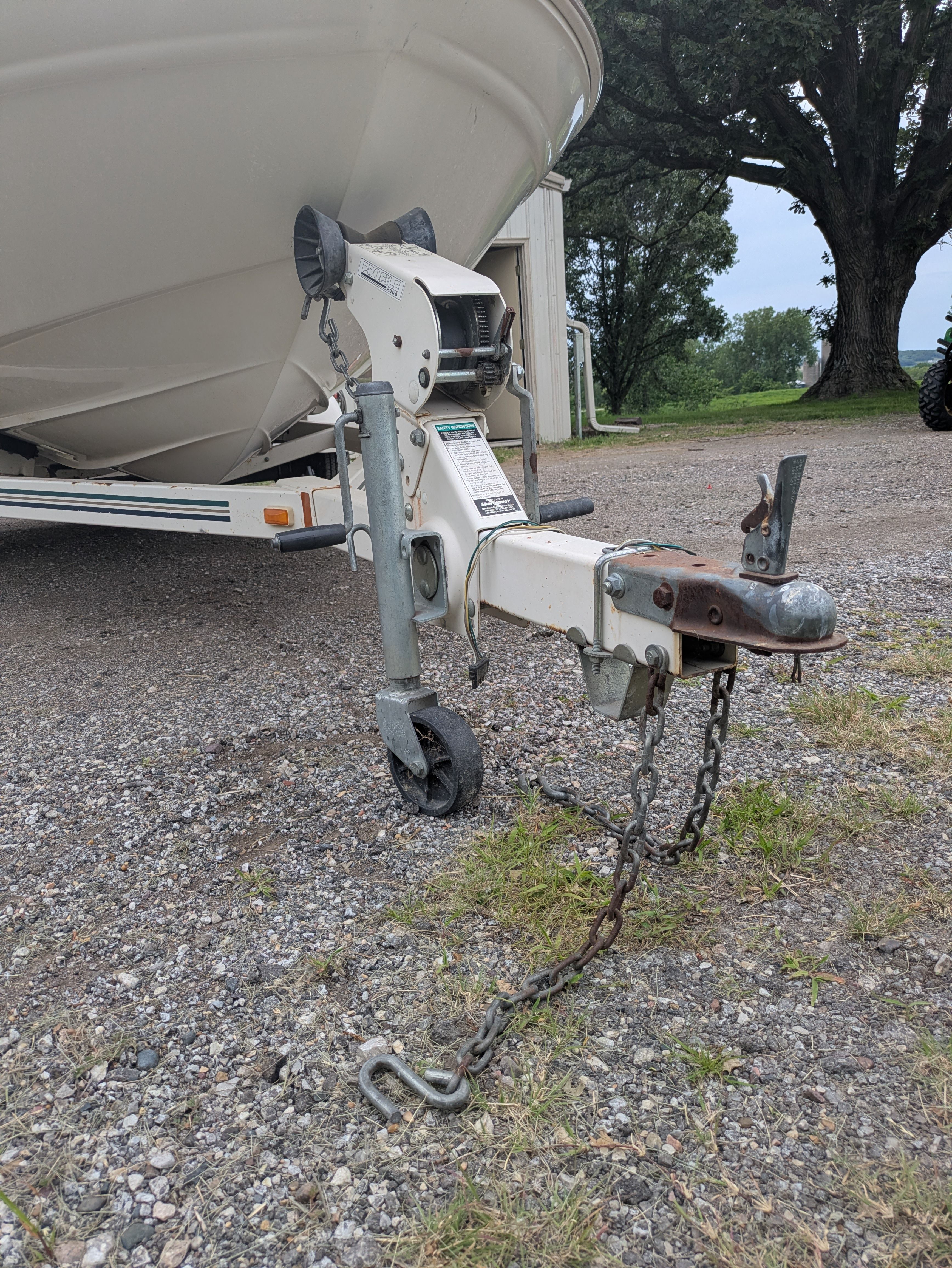 A boat trailer with a Sea Ray 185 Bow Rider, parked on a gravel path.