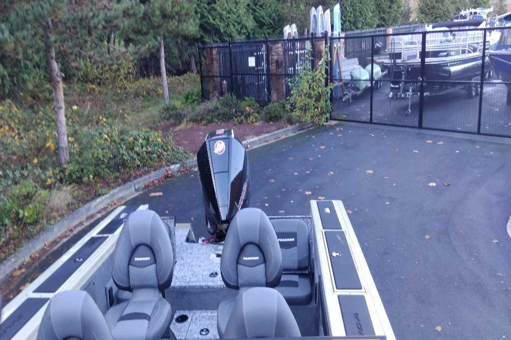 2026 Tracker Targa V-19 Combo boat with outboard motor, parked near a gated area.