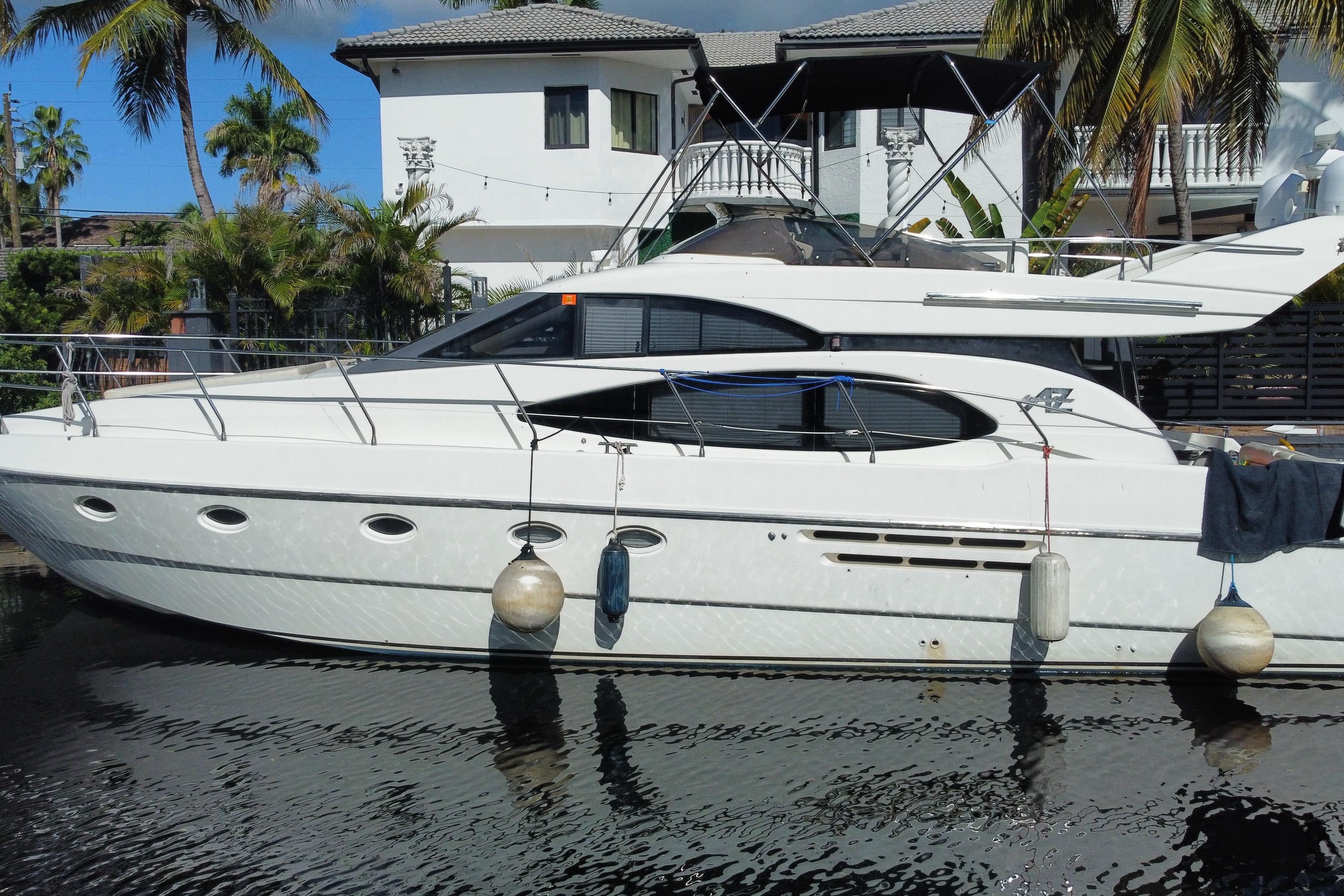 1998 Azimut 52 yacht docked by a tropical waterfront home.