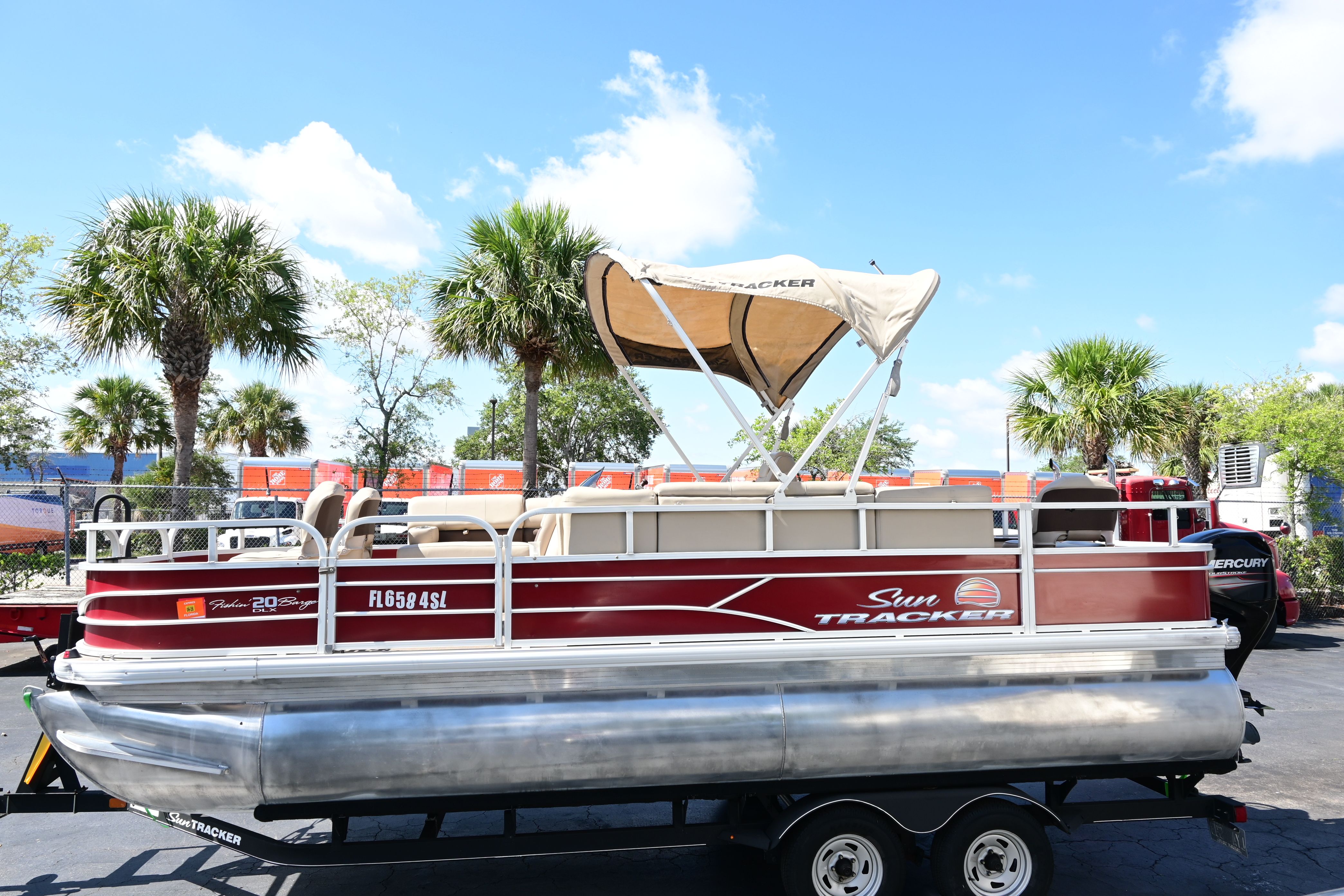 2019 Sun Tracker FISHI pontoon boat with canopy, parked under palm trees.