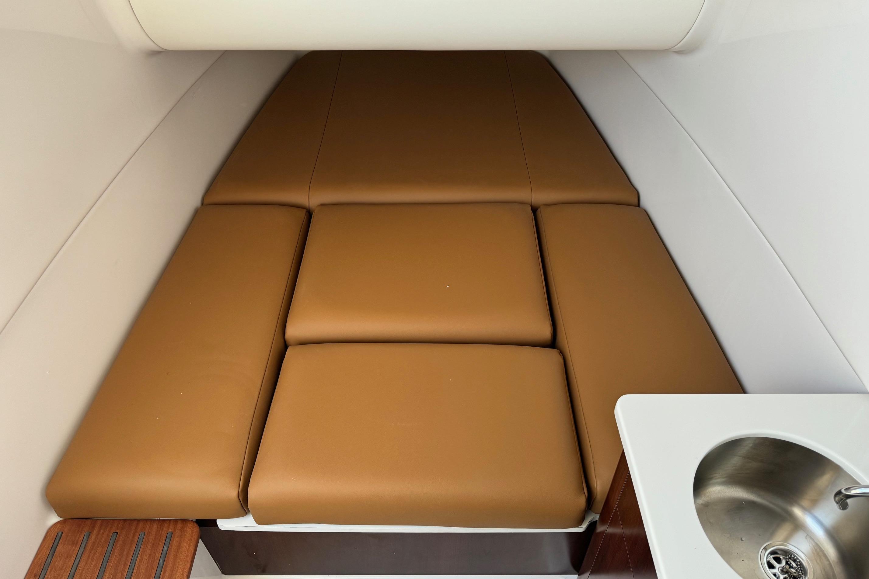 2025 Robalo R360 Center Console cabin with brown cushions and a small sink.